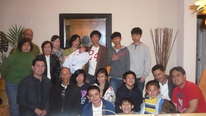 Family members stand and sit together in a warm setting, smiling and celebrating with each other.