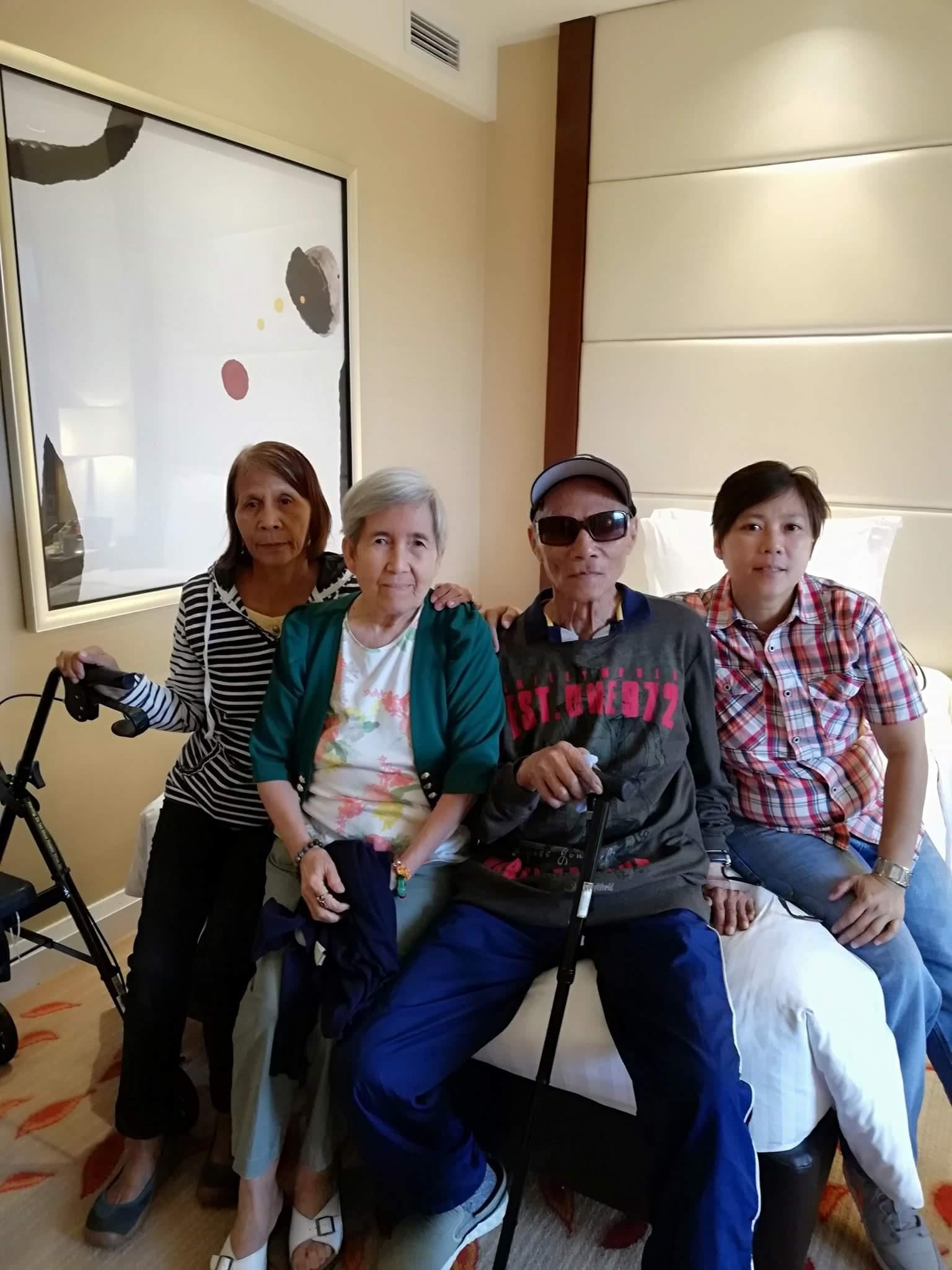 Four people sit together in a room smiling and enjoying each other's company during the day.