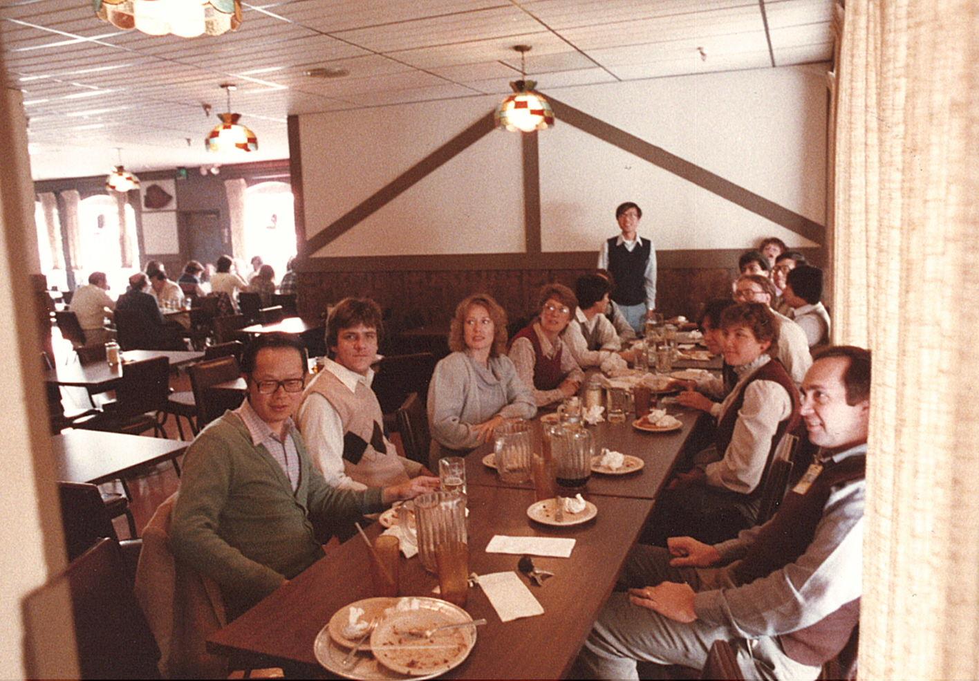 People are sitting together at a long table and enjoying food at a restaurant.