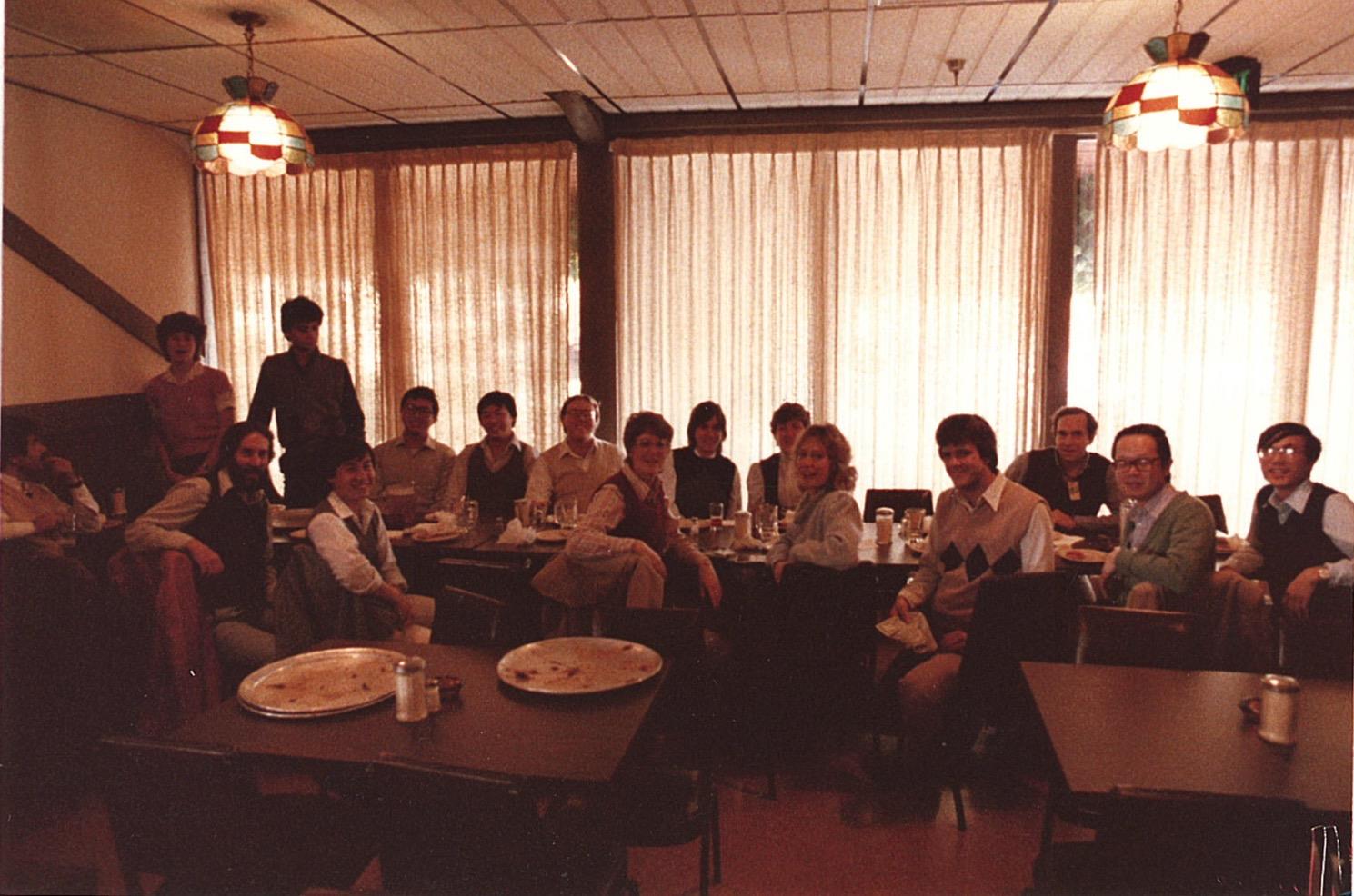 People sit together at tables in a restaurant, enjoying food and sharing moments with each other.