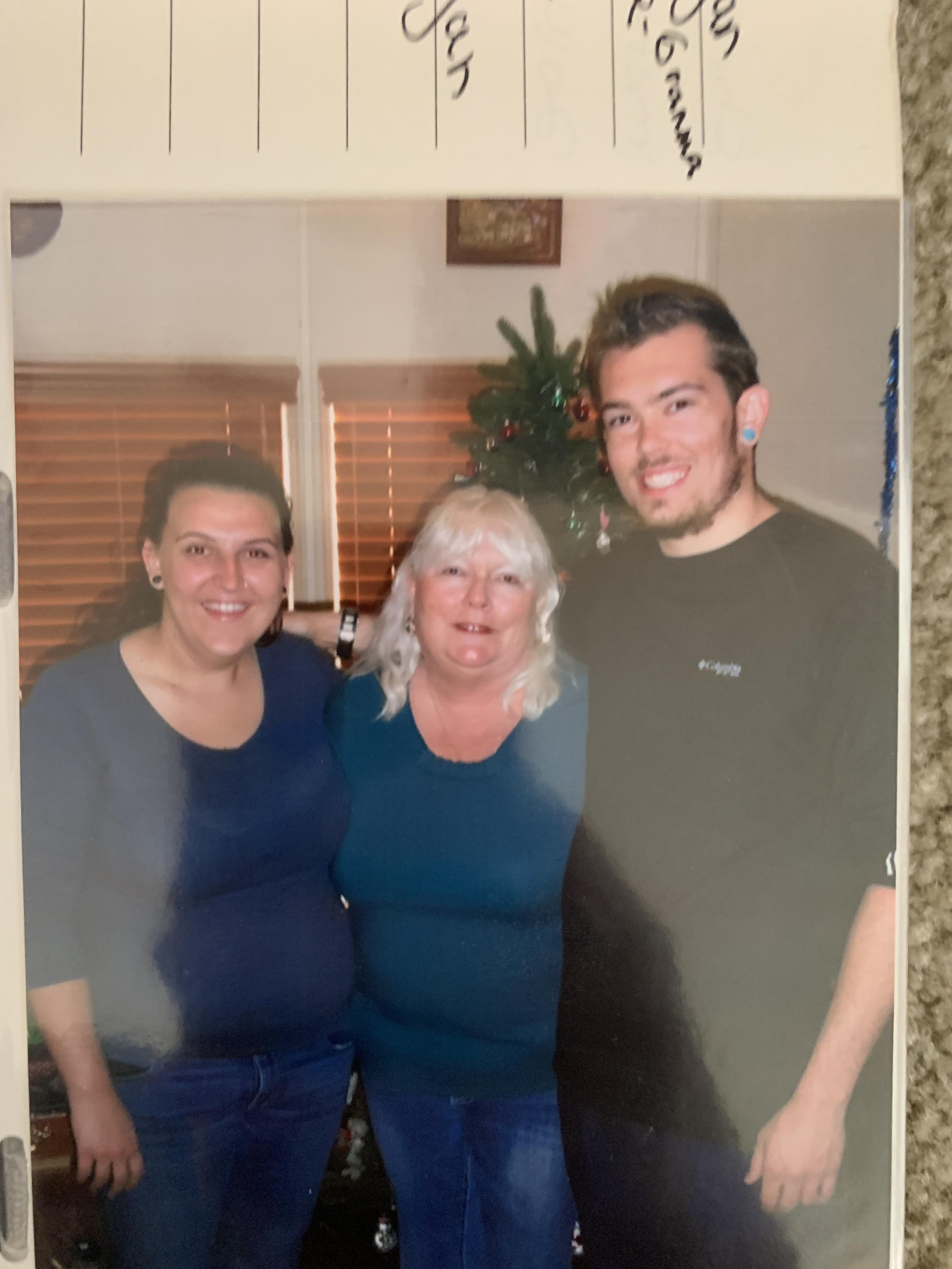 Three people stand together in a cozy living room with natural light coming in.