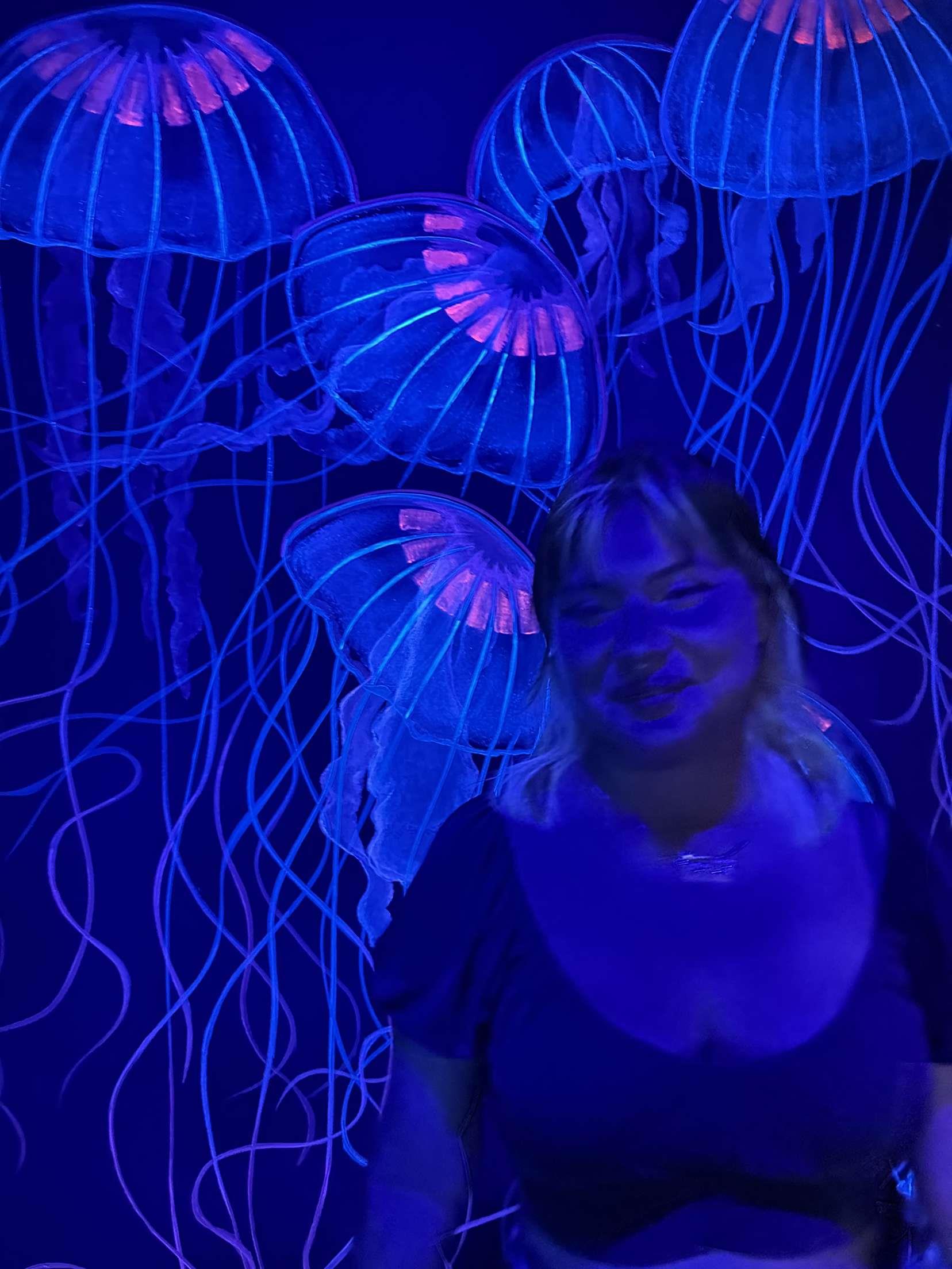 A woman standing in front of a glowing jellyfish