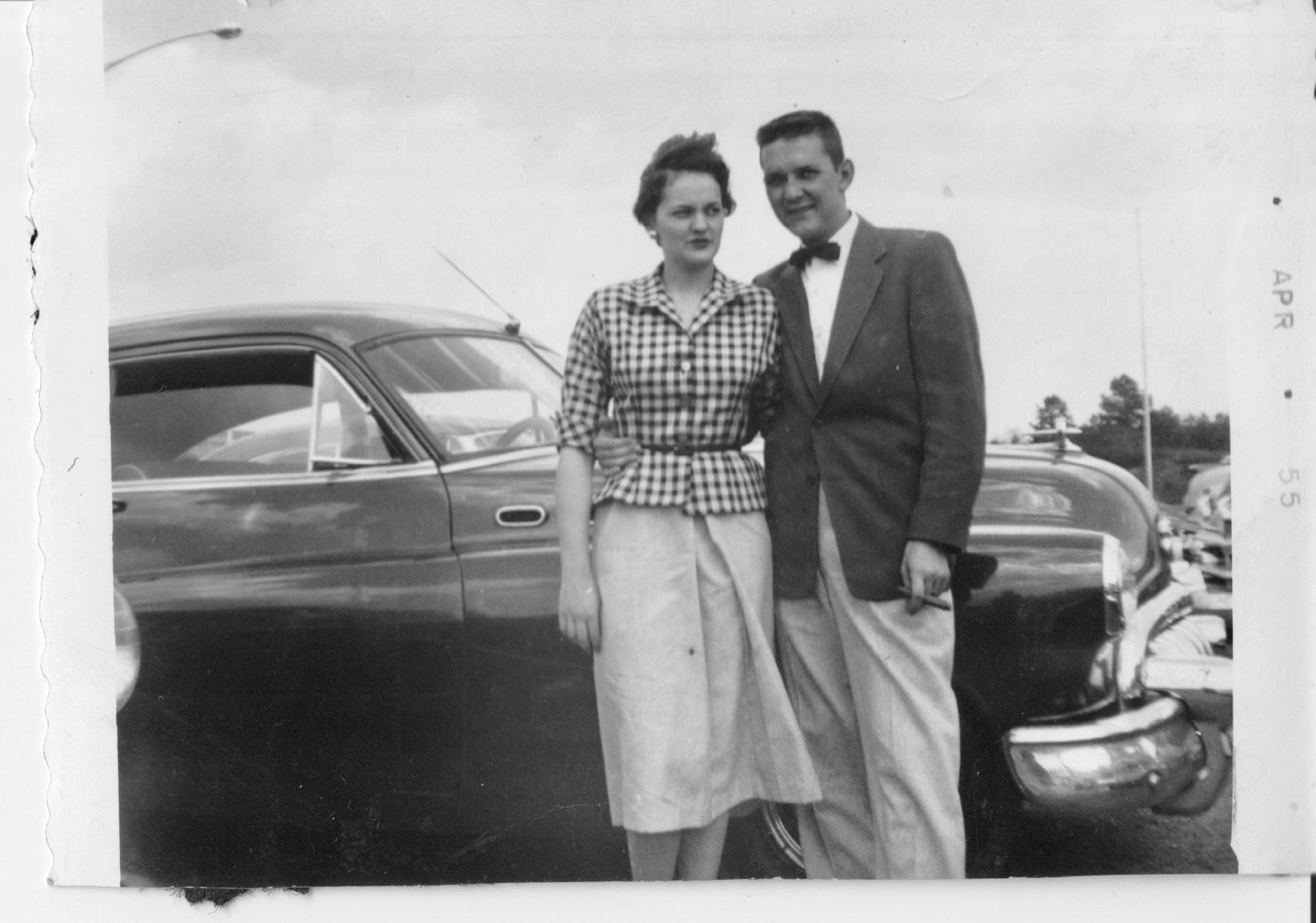 A man and woman standing next to a car