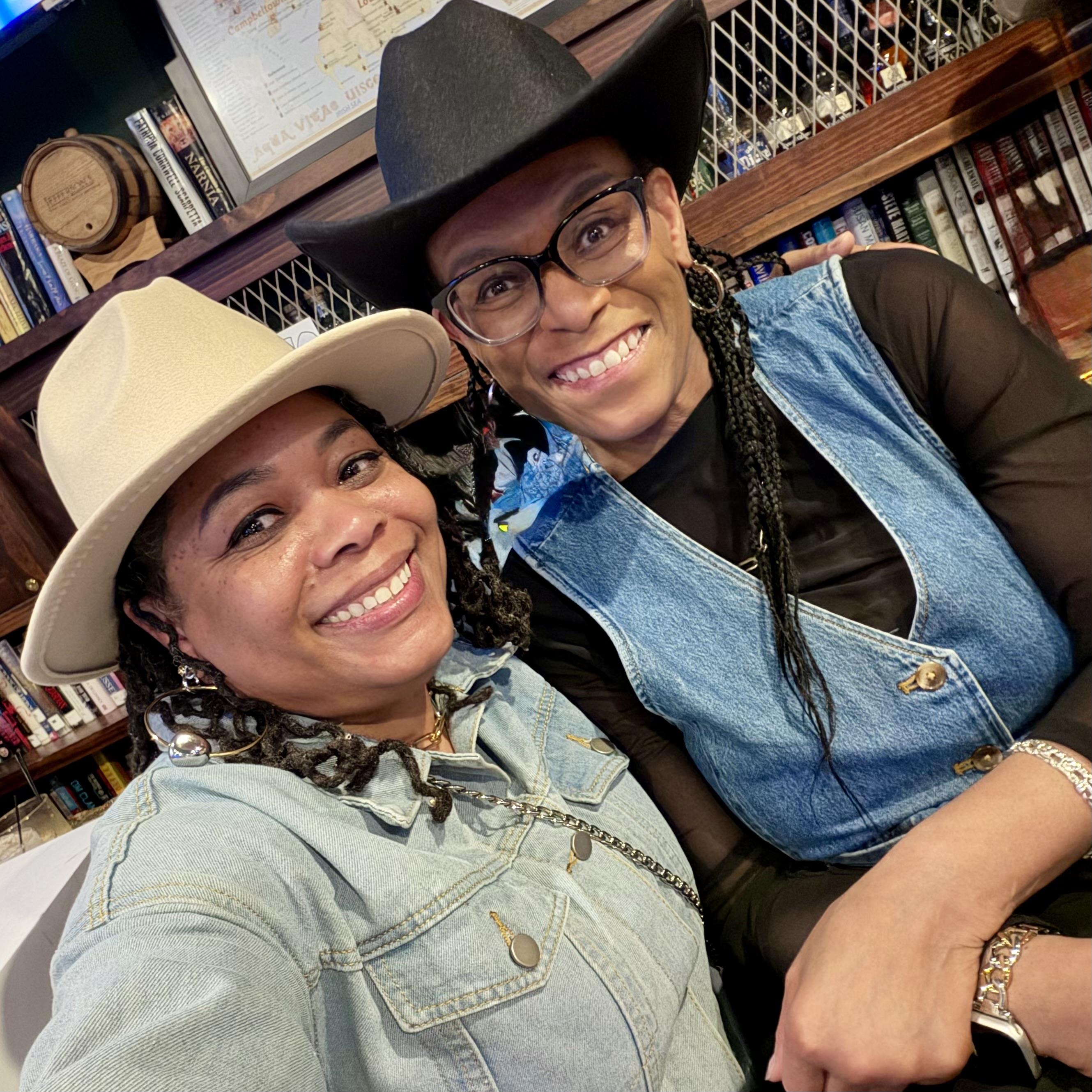 Two women wearing cowboy hats and smiling