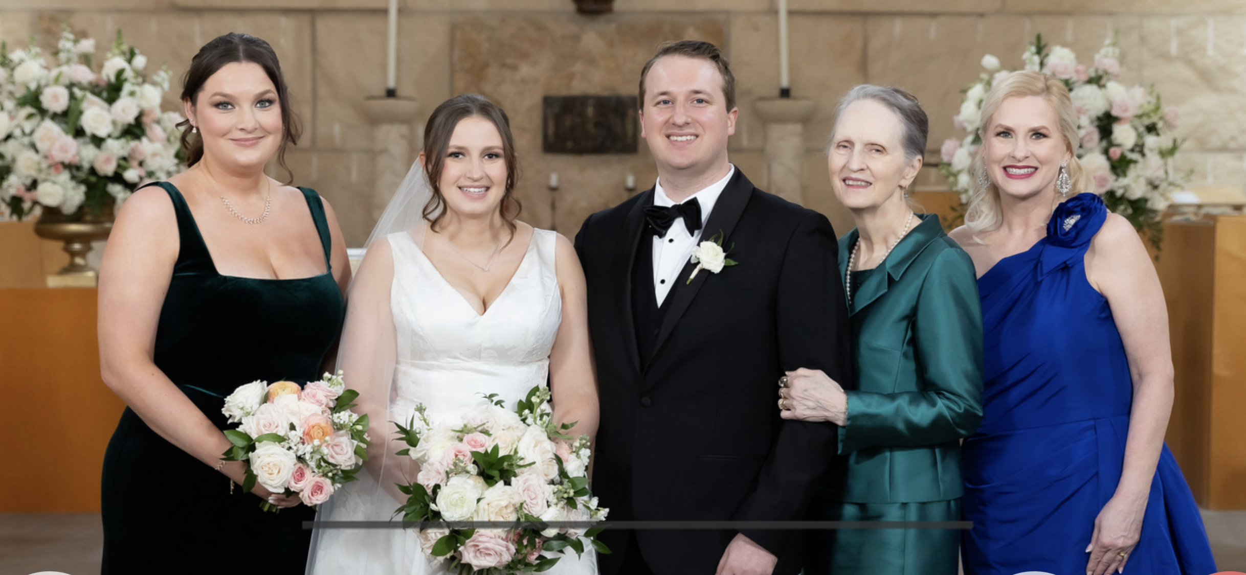 A bride and groom pose for a picture with family members during their wedding in a church.