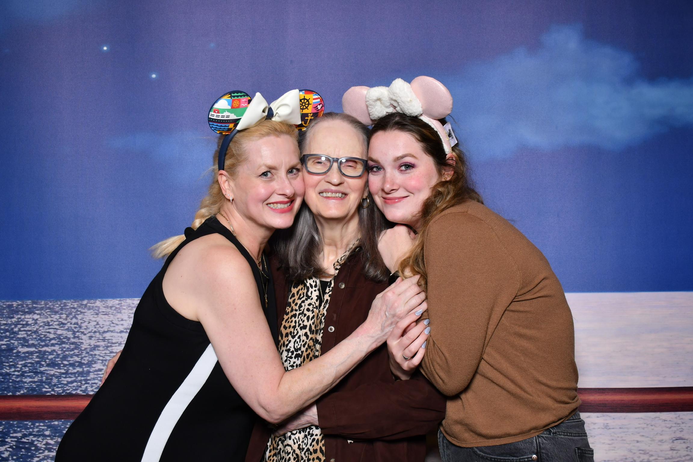 Three women share a joyful moment at a celebration, wearing fun headbands and smiling together.