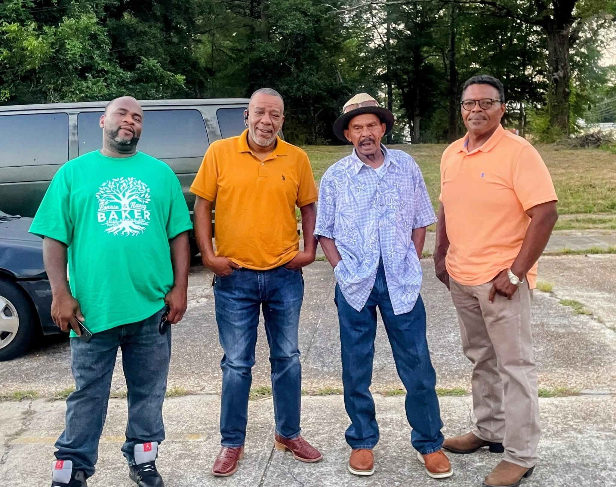 A group of men standing in front of a truck