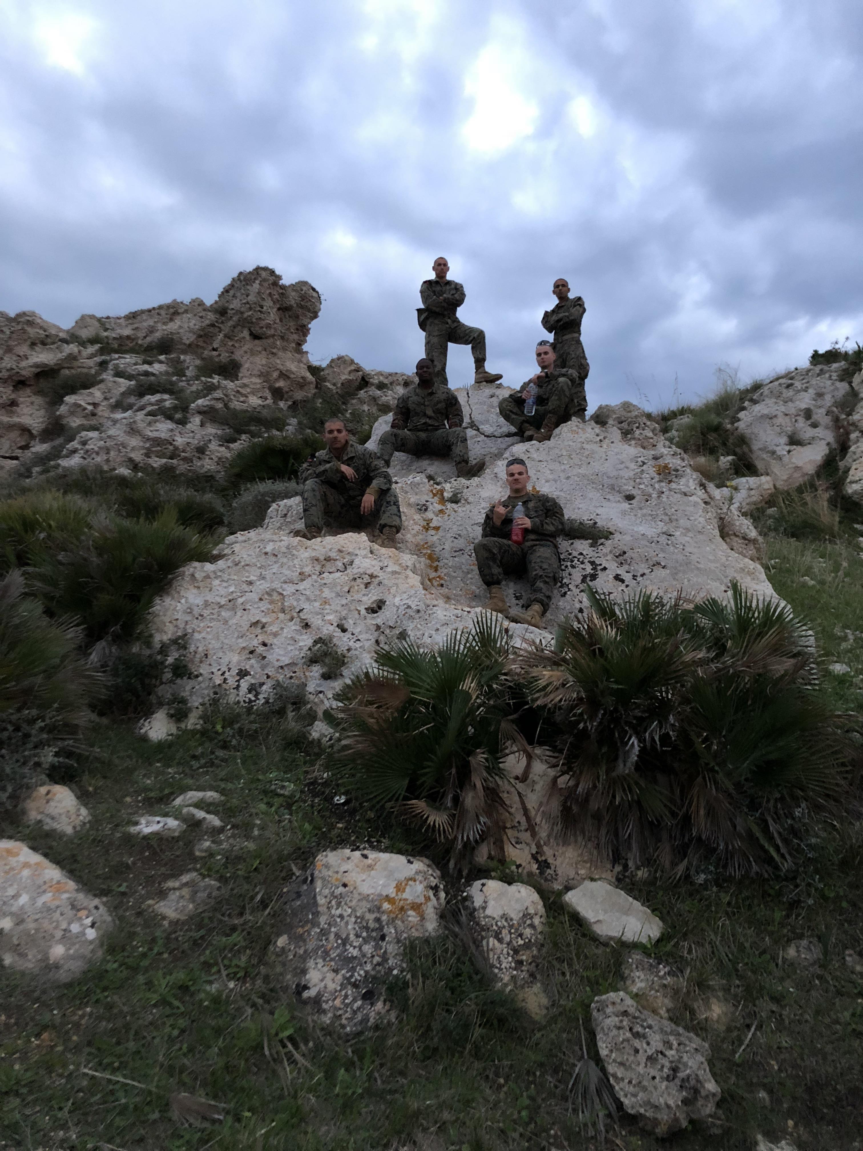 A group of people in military uniforms sitting on a rock