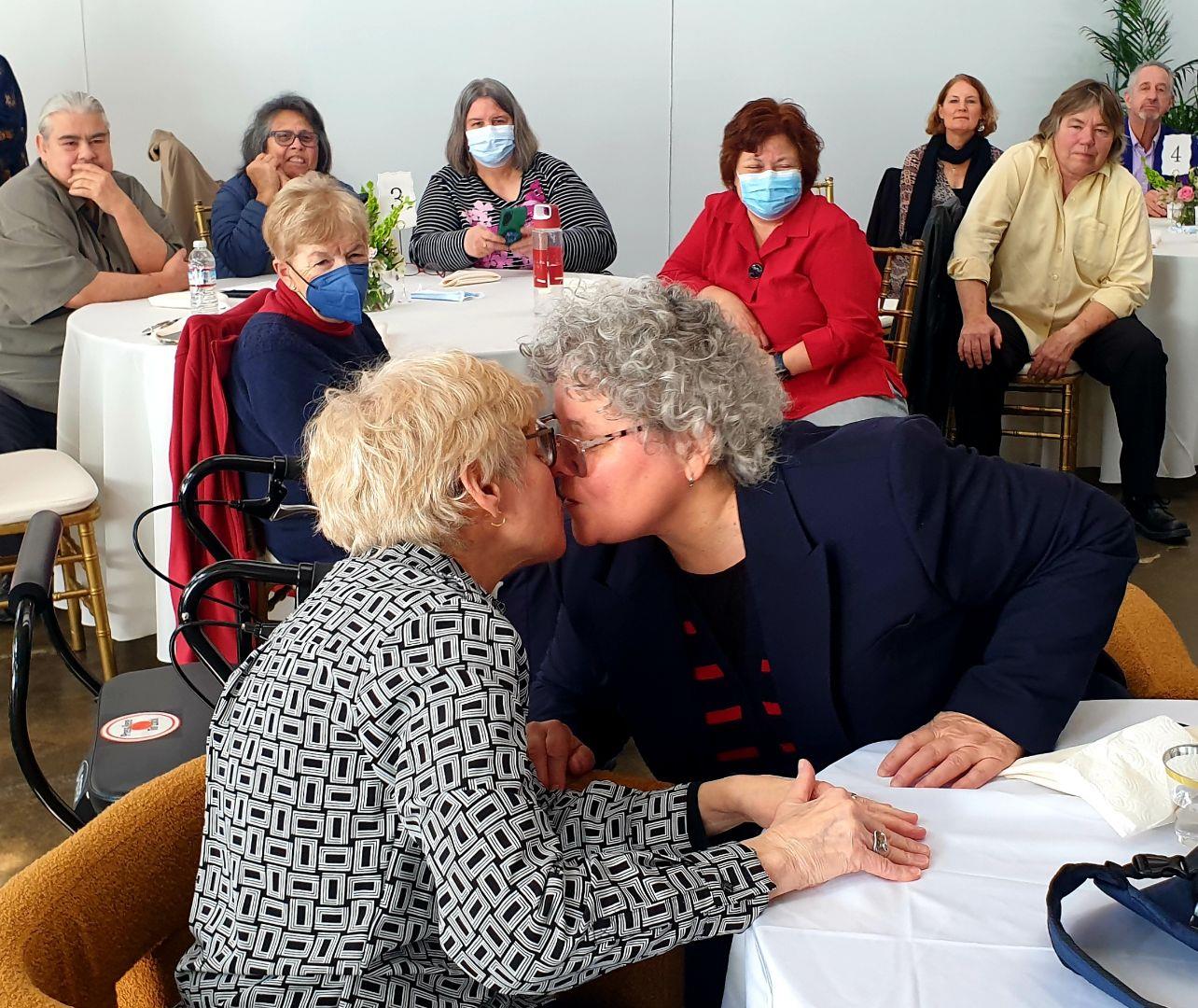 A group of people sitting around a table kissing