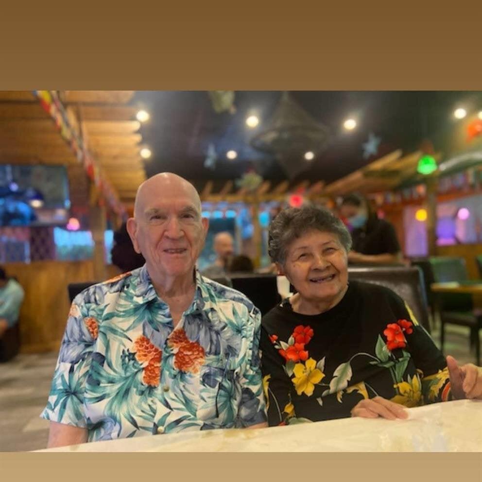 A couple smiles at each other while enjoying dinner at a restaurant.