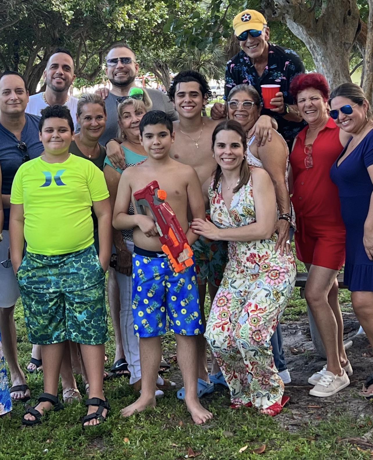 People are smiling and standing together at a park during a summer gathering.