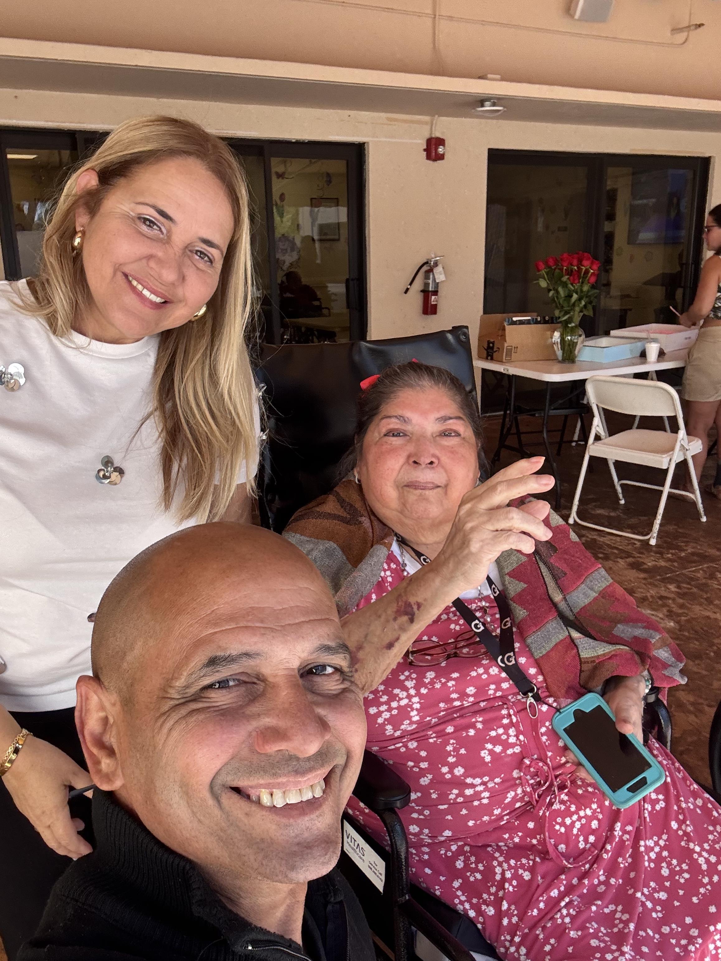 Three individuals enjoy time together at a community center. They are smiling and engaging.