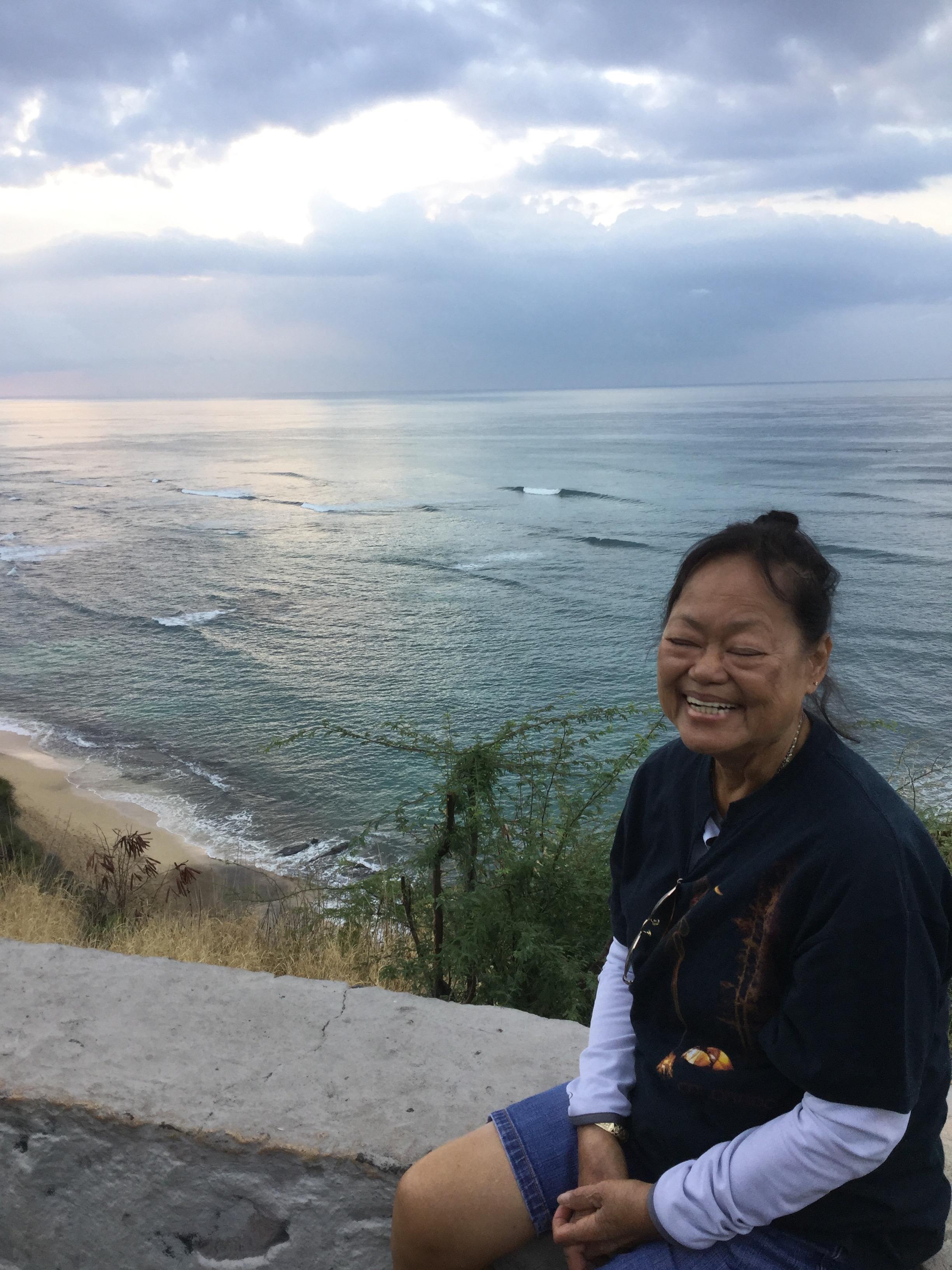 A woman sitting on a ledge with a body of water in the background