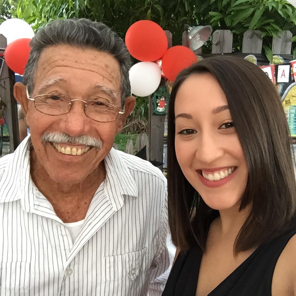 A man and a woman smile while taking a selfie at a joyful gathering with festive decorations.