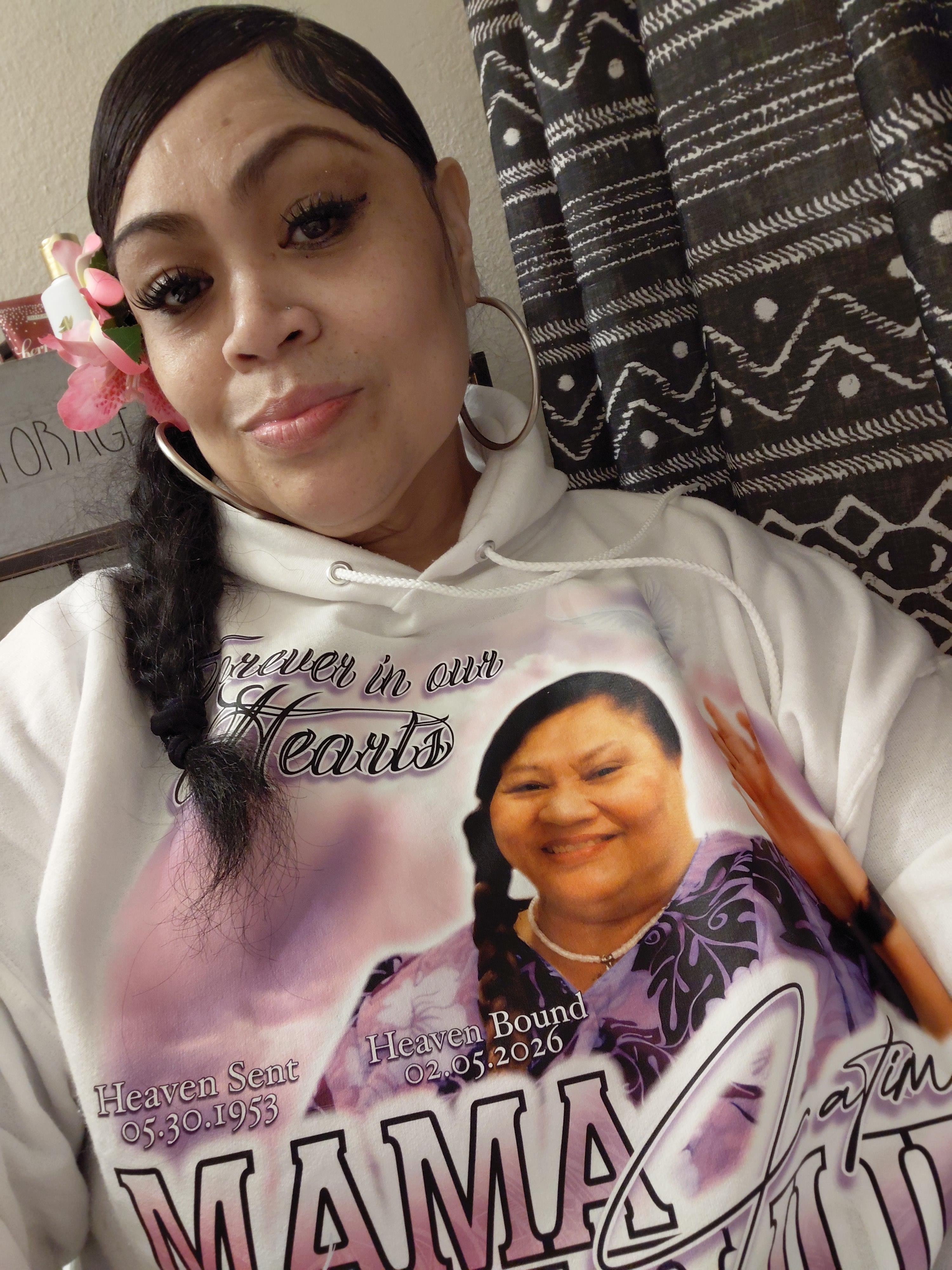 A woman sits comfortably indoors wearing a customized hoodie with a printed picture.