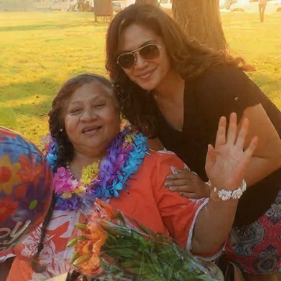 Two women enjoy a sunny day in the park surrounded by flowers and balloons.