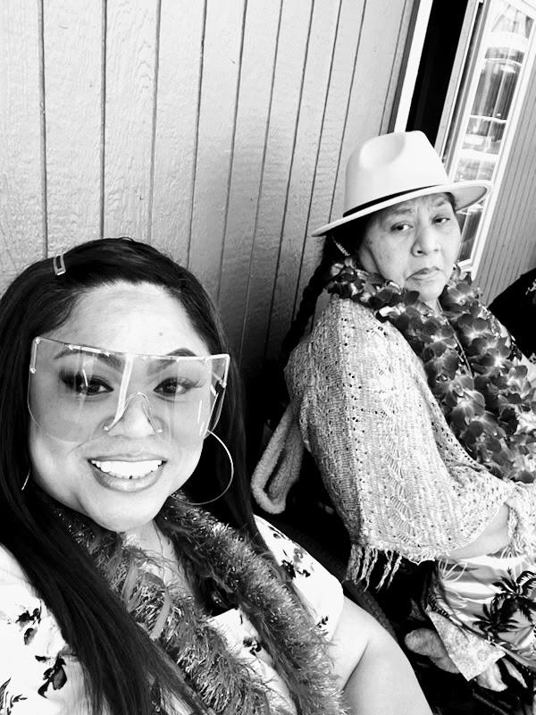 Two women enjoy a social event outdoors, with one smiling and the other looking serious.