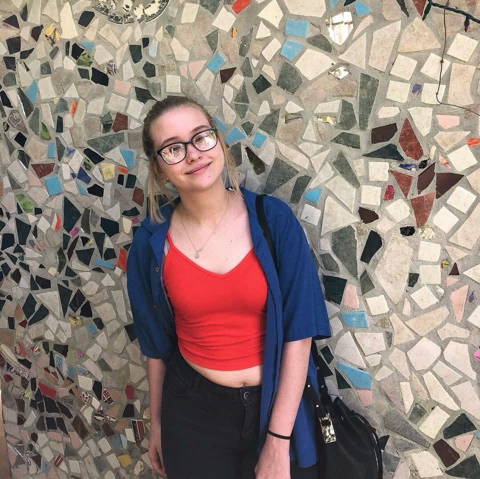 A woman standing in front of a mosaic wall