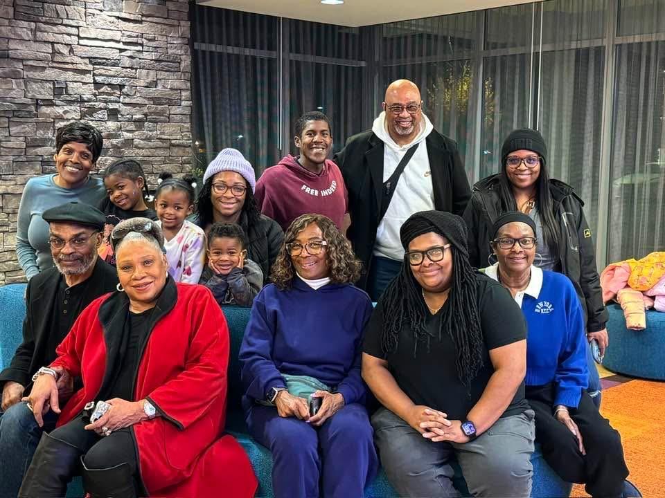 Many people smile and gather together at a social event. They appear happy and engaged.