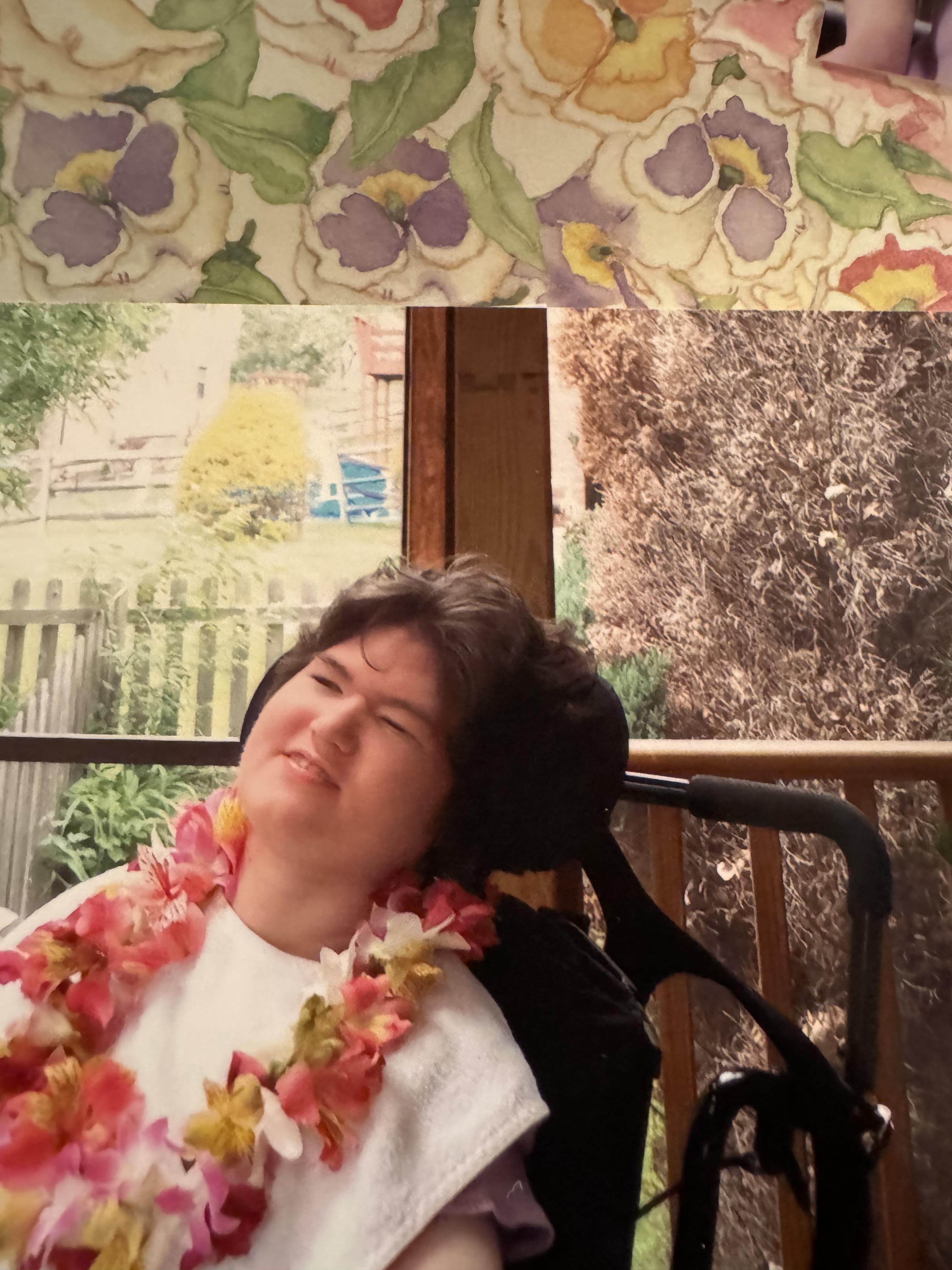 A woman in a wheelchair with a flower necklace