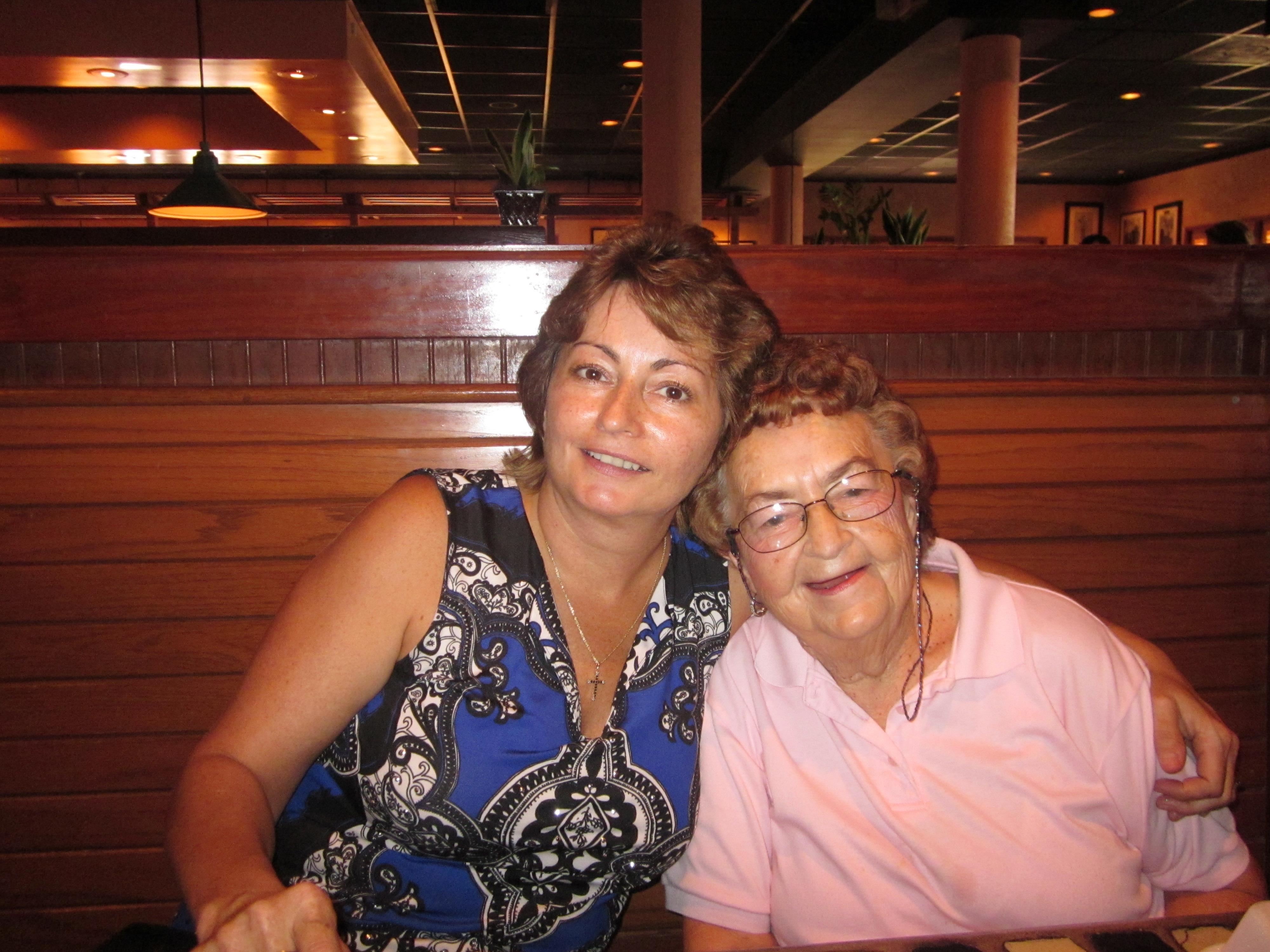Two family members are sitting closely at a restaurant table during dinner time.