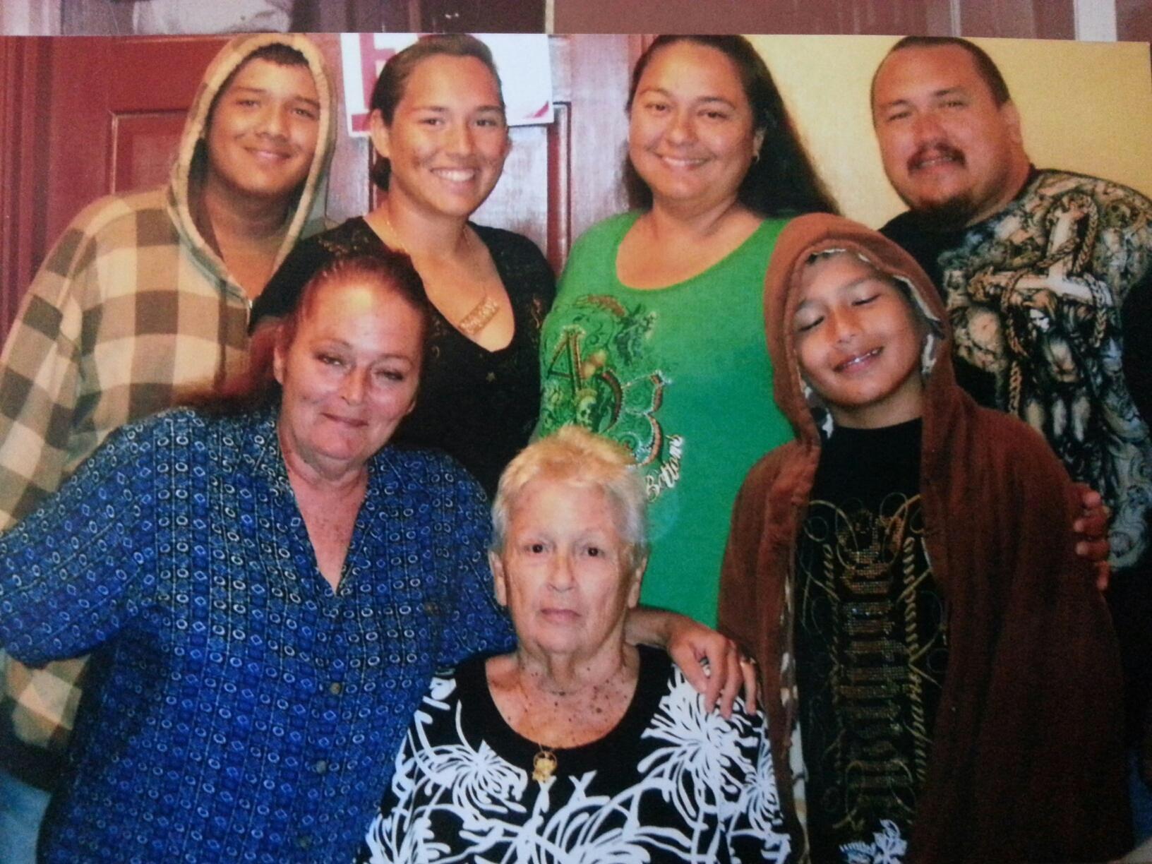 Seven family members stand together in a home, sharing laughter and smiles during a gathering.