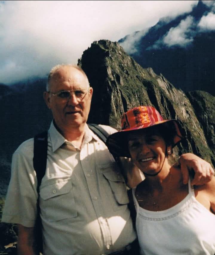 A man and a woman stand together at Machu Picchu beside a mountain.