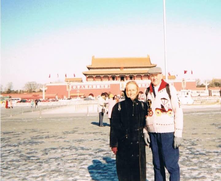 Two people pose for a picture in front of the Forbidden City in Beijing on a cold day.