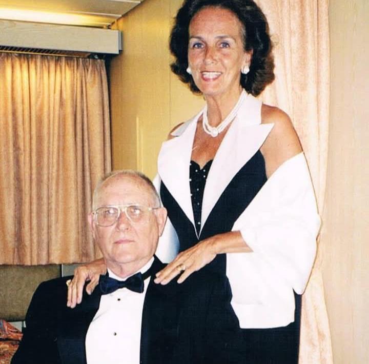 A man and woman stand together at a formal gathering.