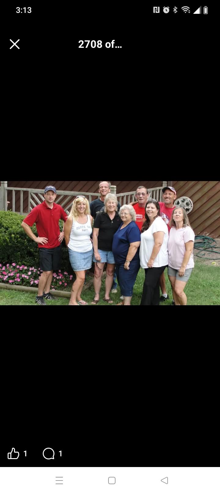 A group of people stands together in a garden smiling and enjoying their time at a summer event.