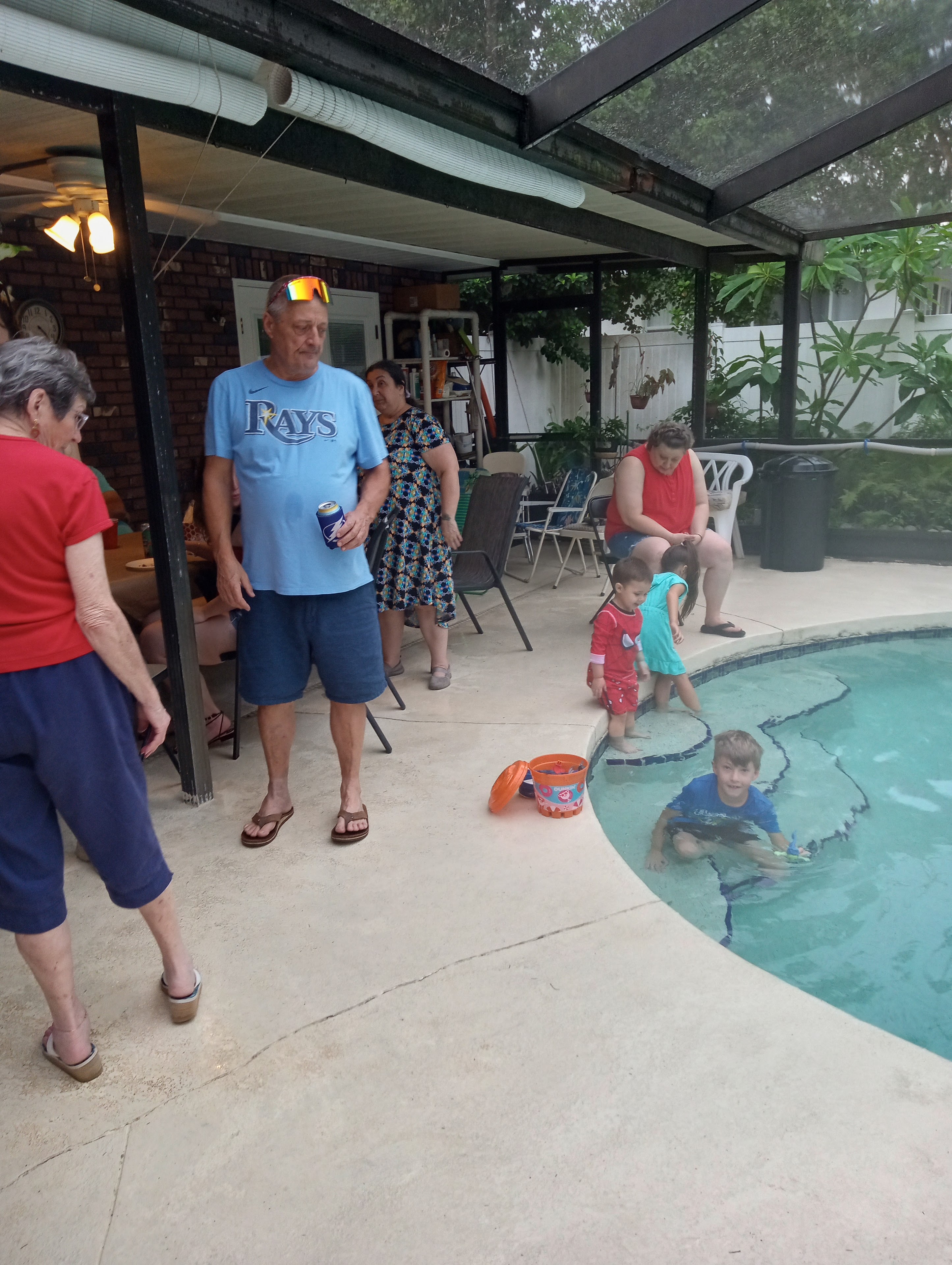 People relax by the pool, with kids playing and adults chatting in the afternoon.