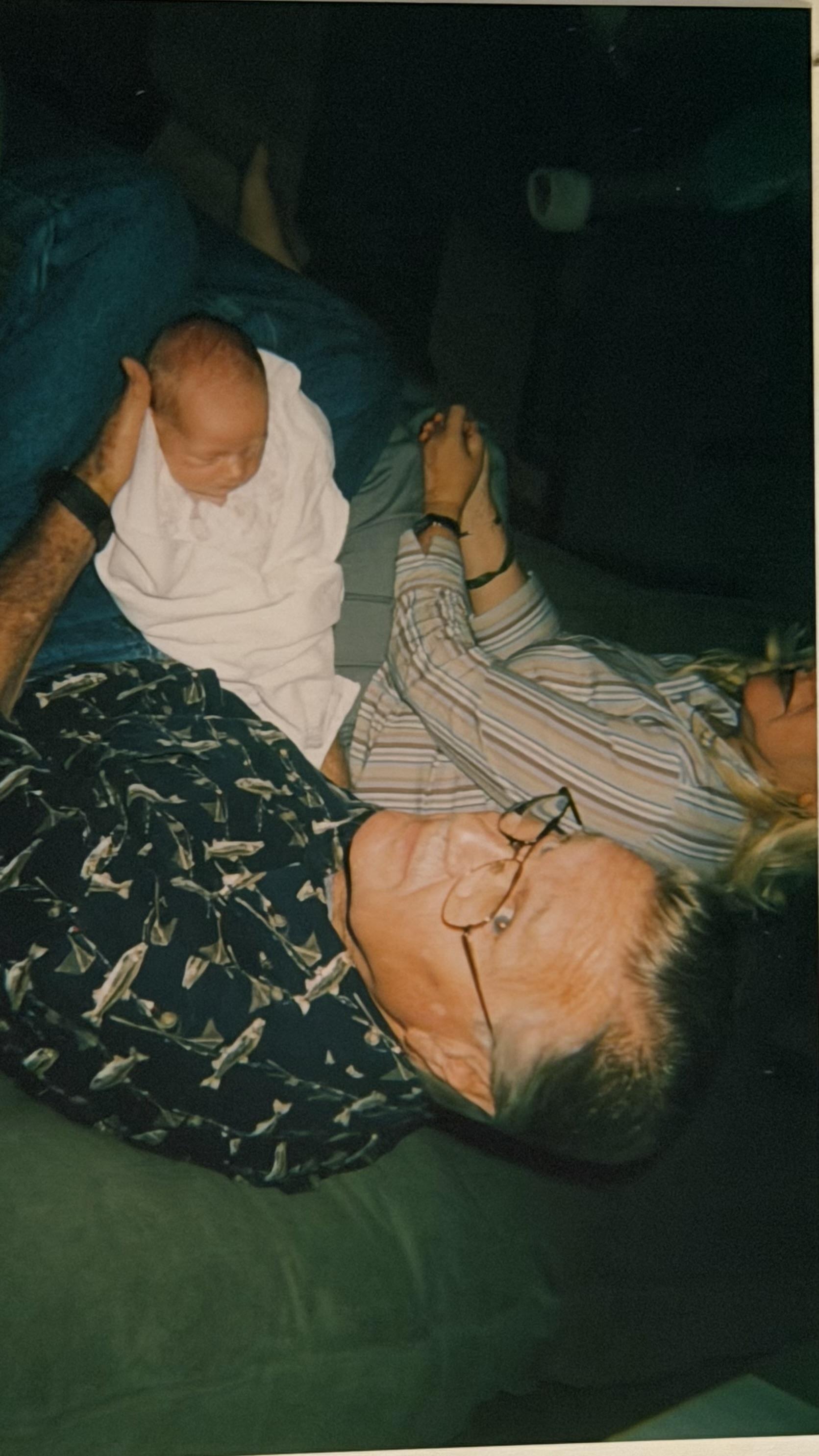 A man and woman lying on a couch with a baby