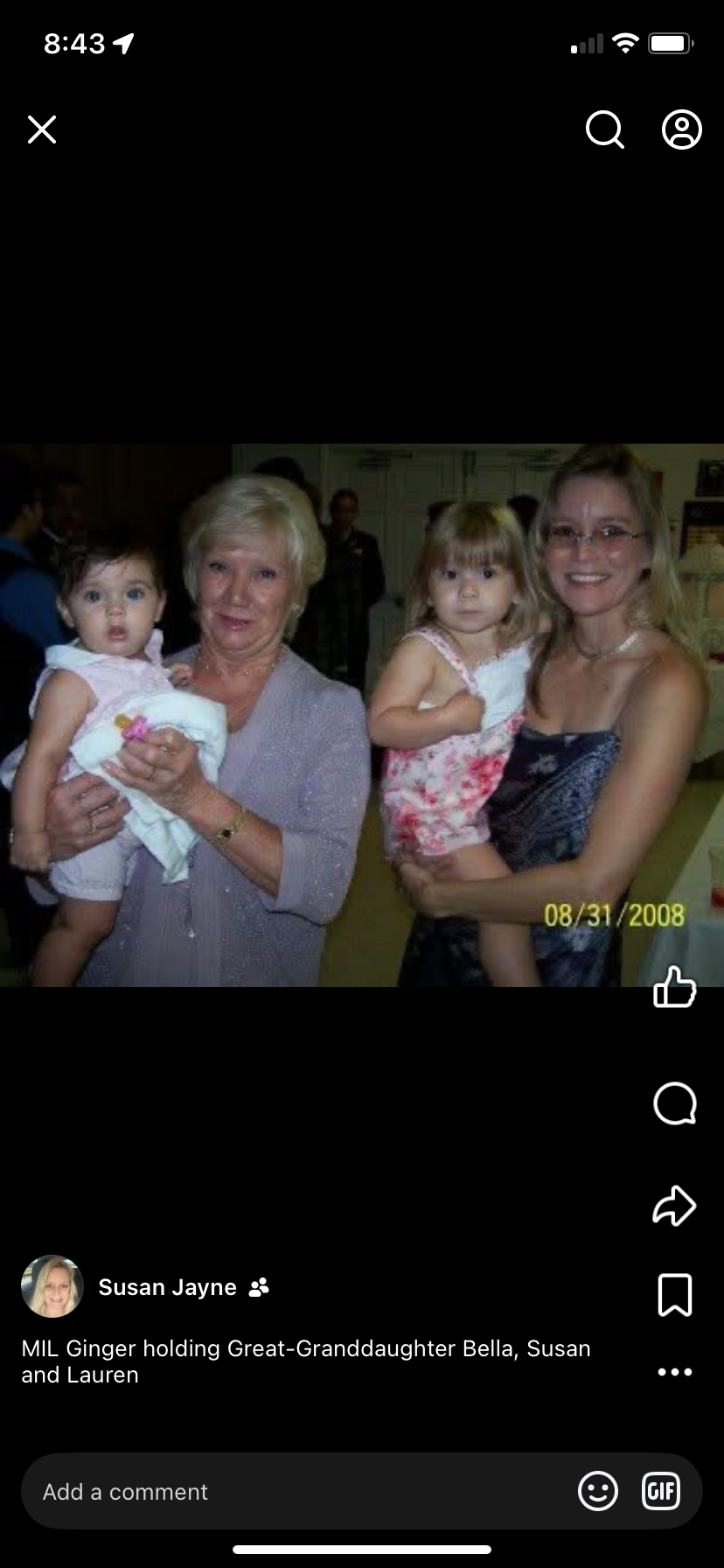 Two adults hold young girls during a gathering at an event. The setting shows family interaction.