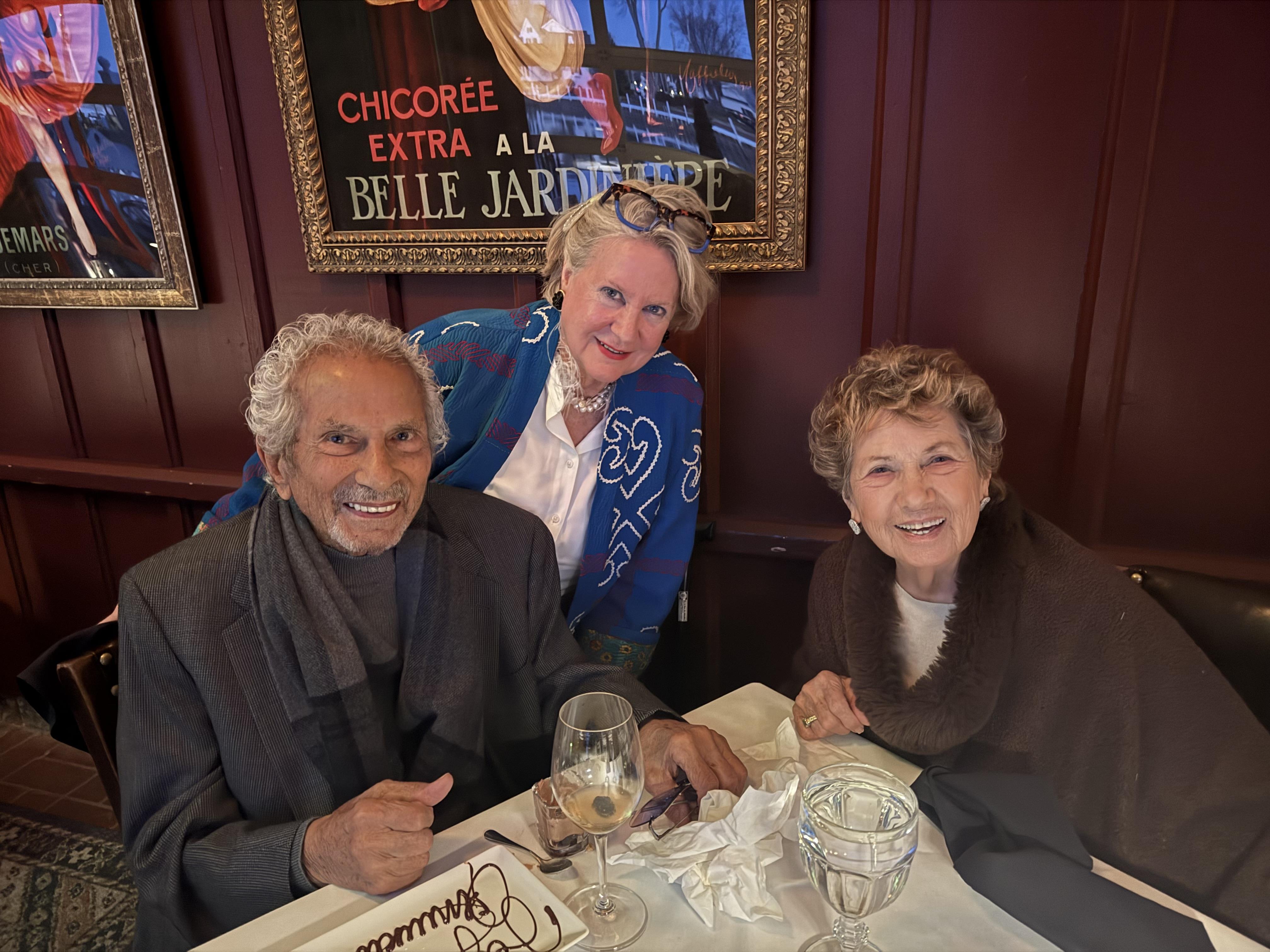 Three friends enjoy a meal and share stories at a restaurant during the afternoon.