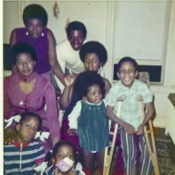 A group of adults and children gather in a living room for a snapshot with smiles and joy.