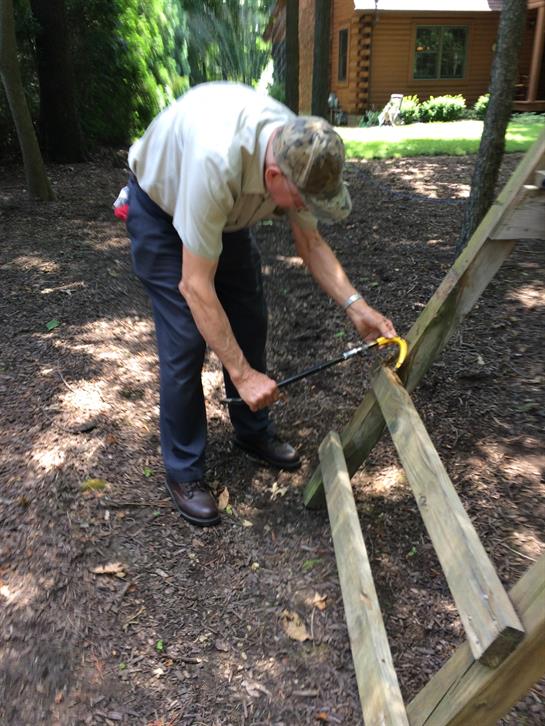 A man using a saw to cut a wood beam