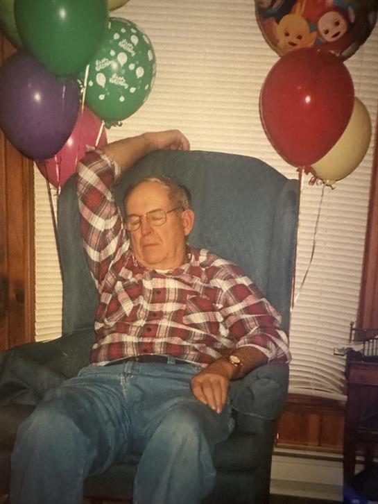 A man sitting in a chair with balloons