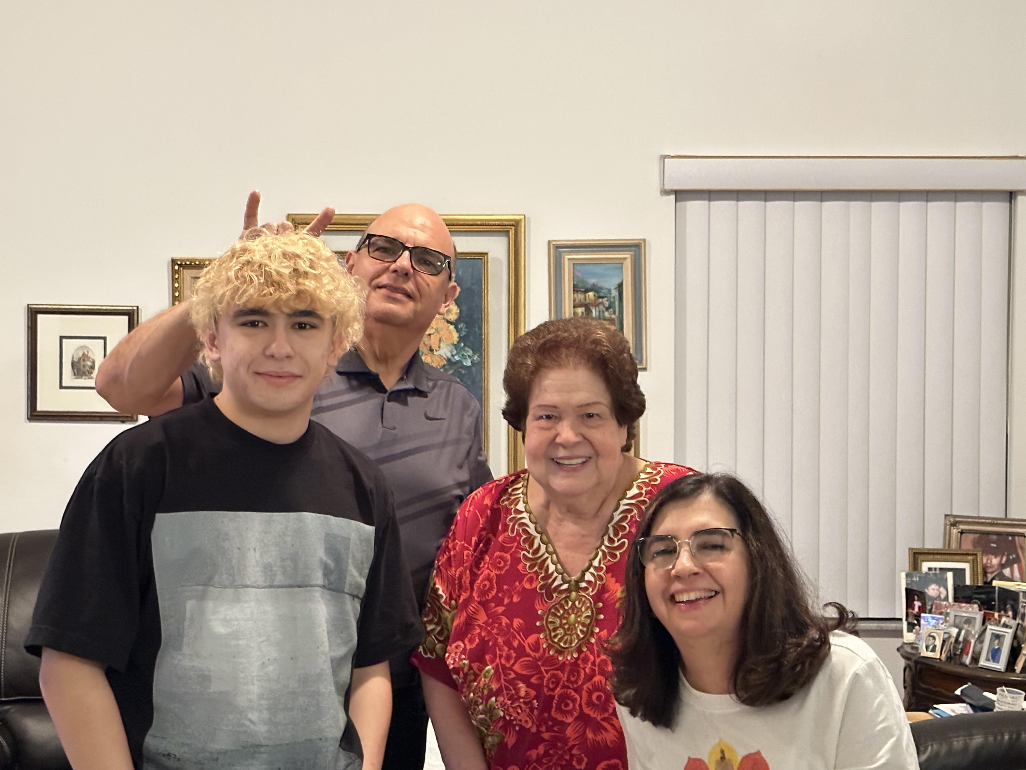 Four family members smile and enjoy time together in the living room after dinner.