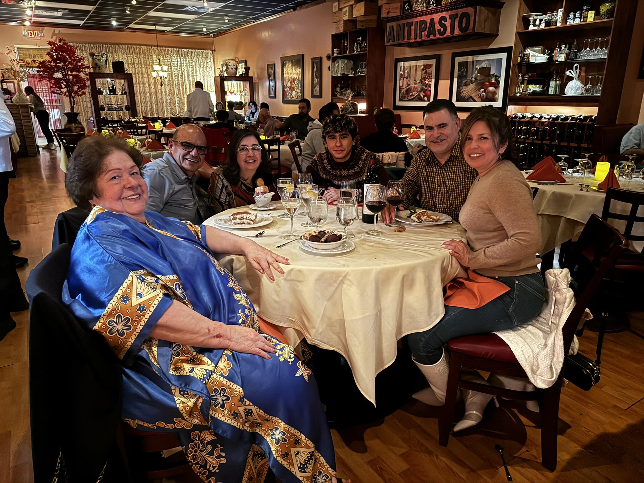 Friends gather around a table, enjoying dinner, drinks, and laughter together.