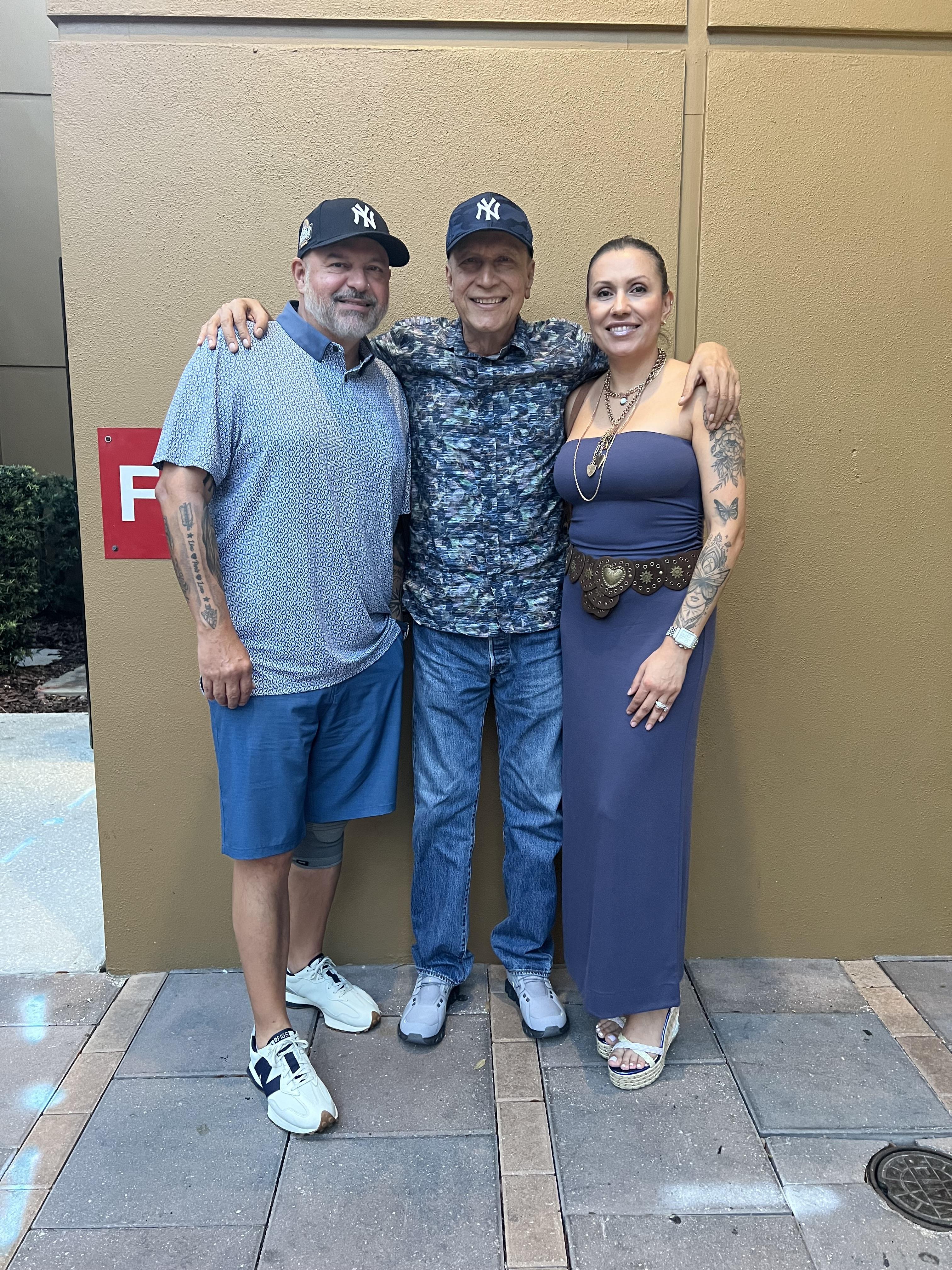 Three people pose together for a picture at a gathering in a social setting.