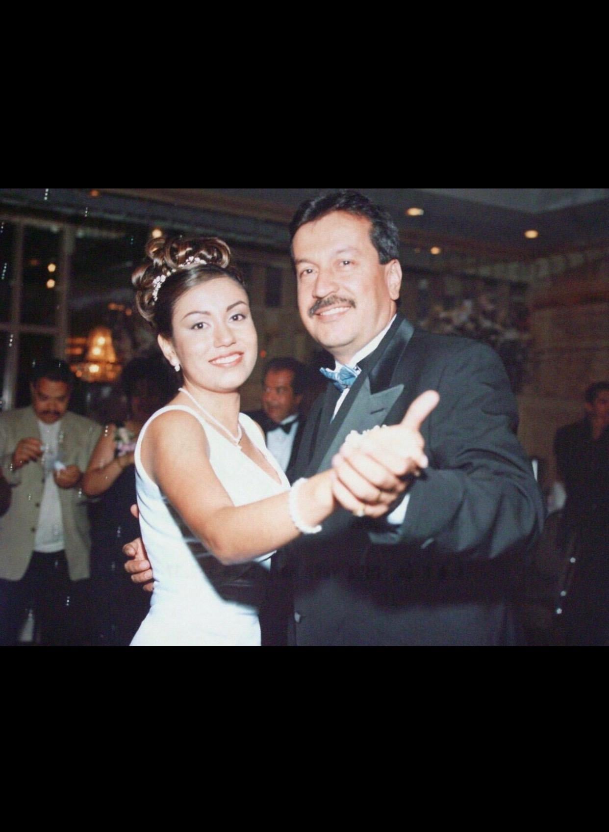 A couple enjoys dancing at a celebration in a banquet hall with others present around them.