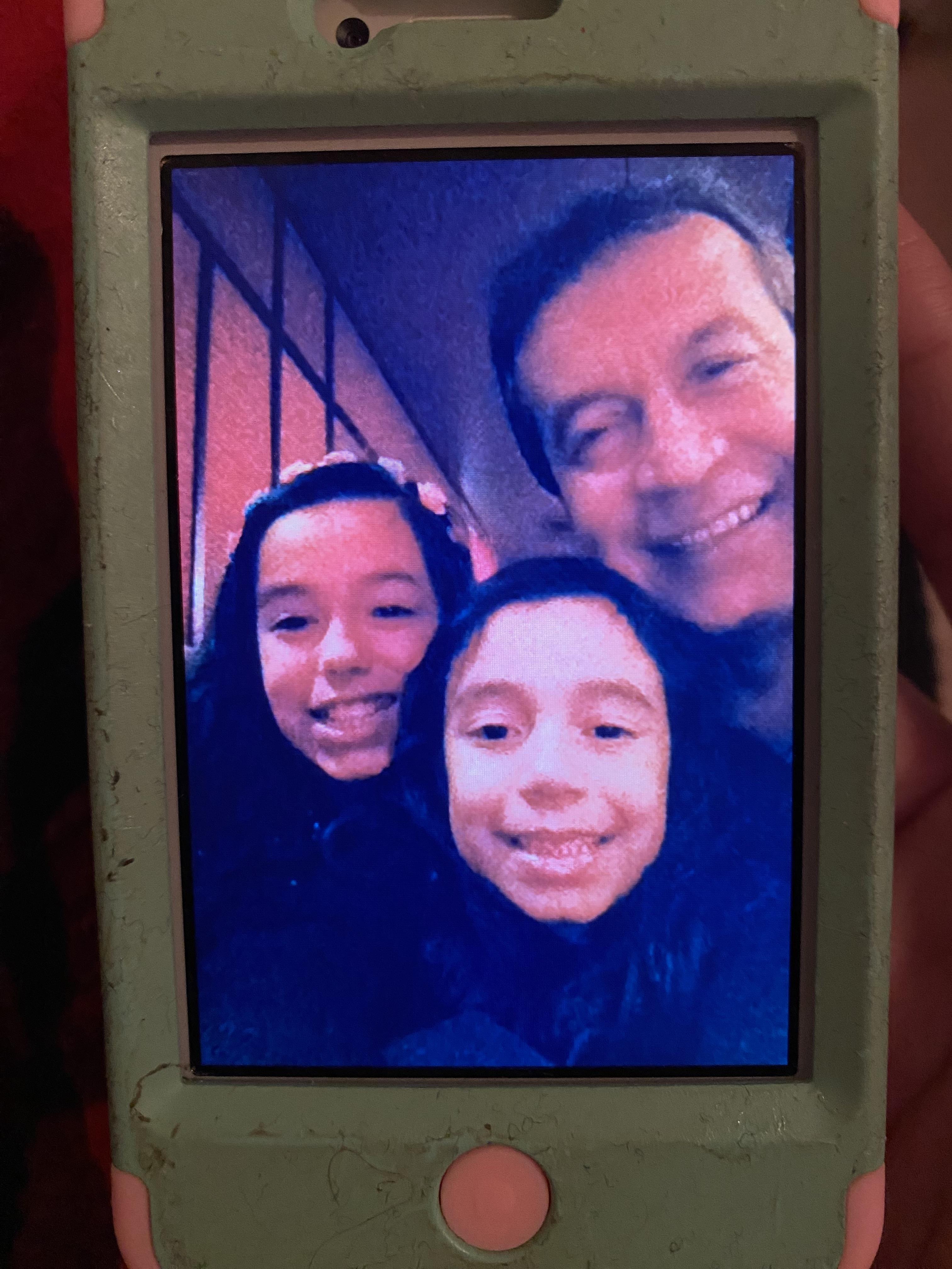 Two girls and a man take a selfie inside a building during a fun moment together.