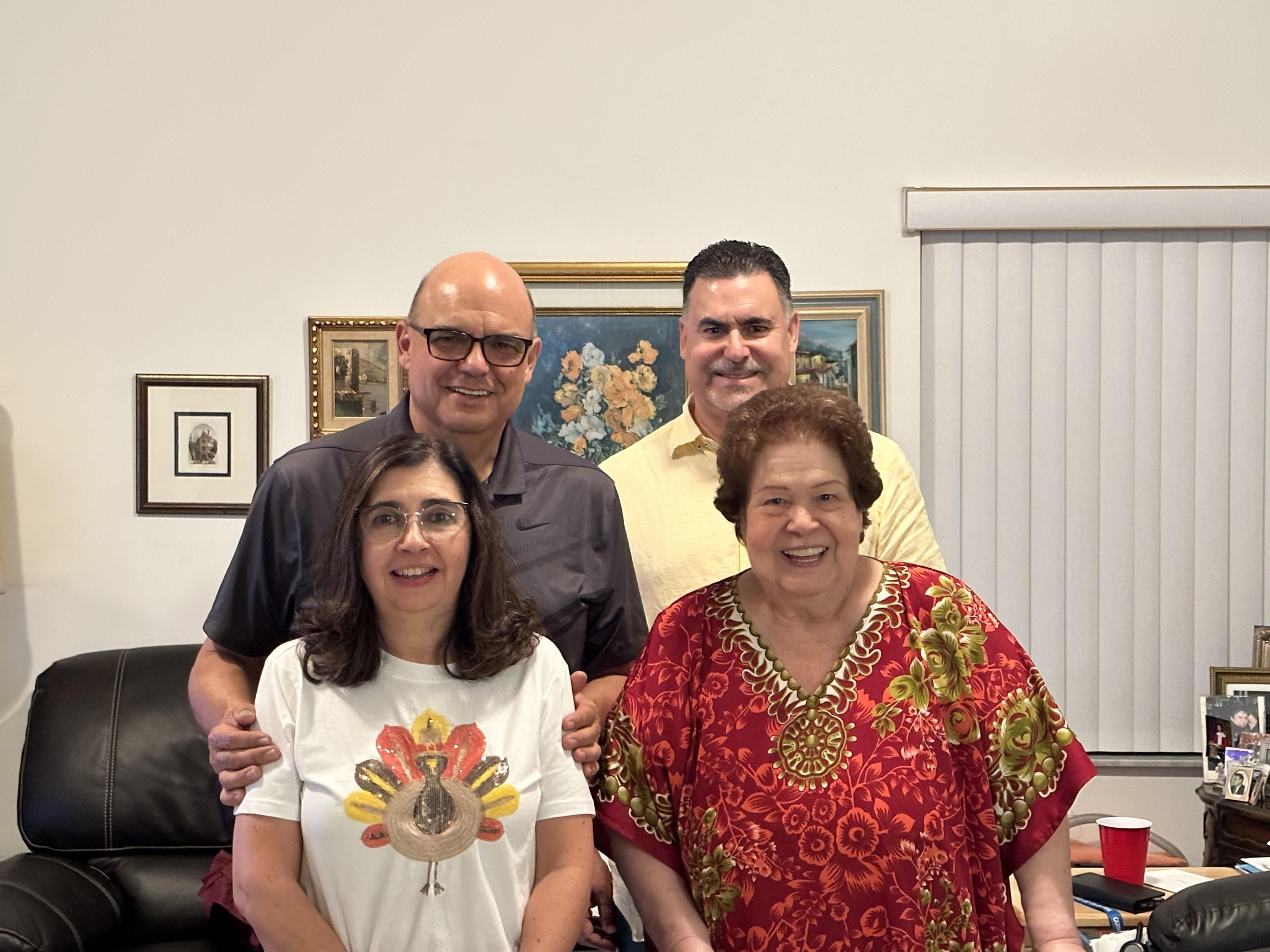 A group of four people stands together in a living room, sharing smiles and laughter.