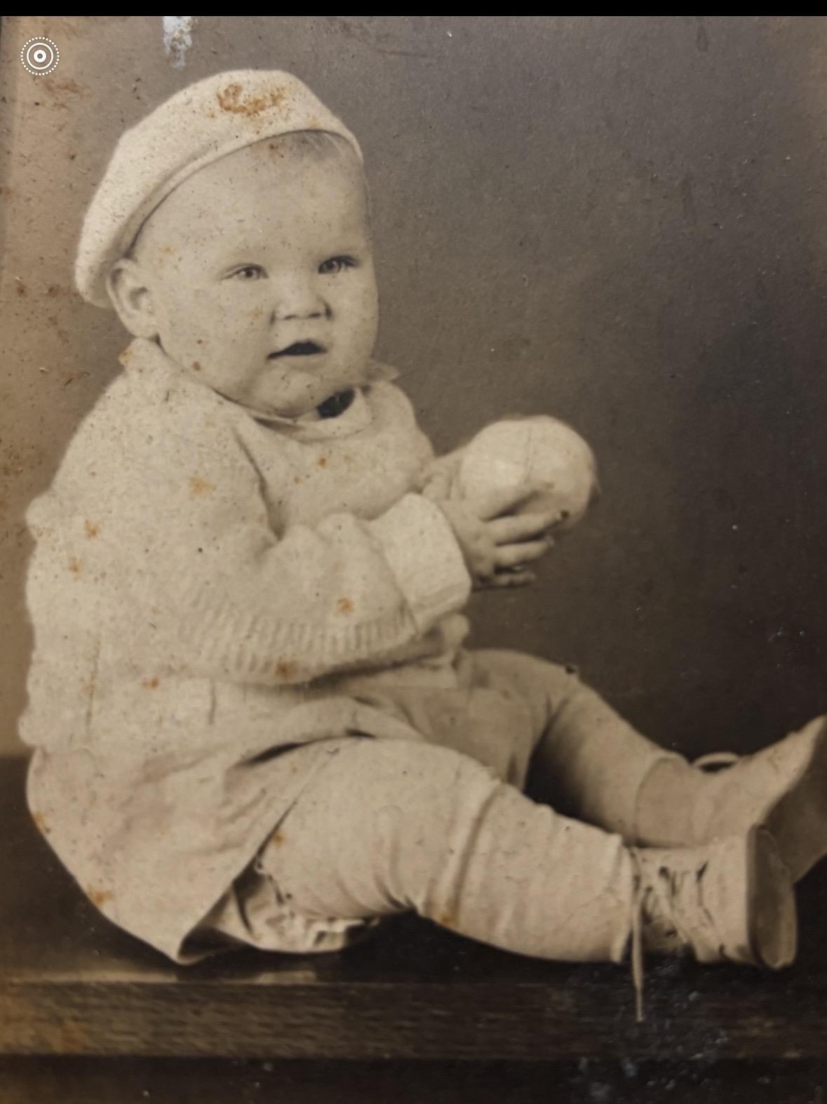 A baby sitting on the floor holding a ball