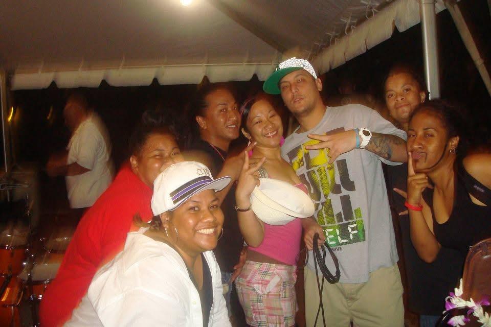 A group of friends smiles and poses in a tent at a social gathering at night.