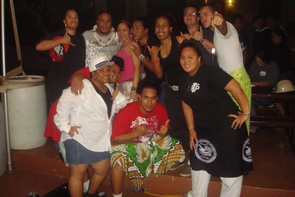 Friends gather and smile for a picture at a lively party in a warm setting at night.