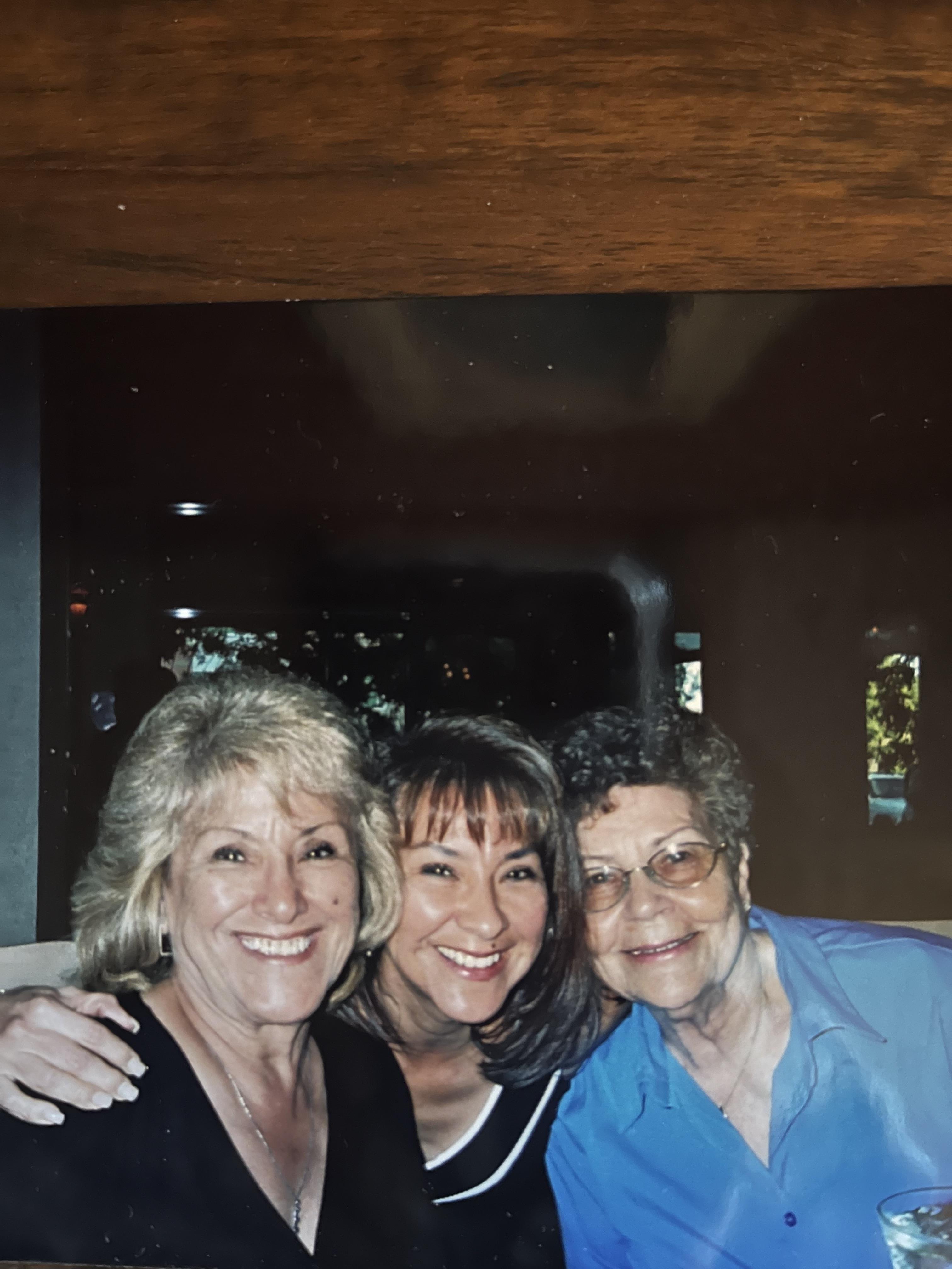 Three women are enjoying time together in a cafe, smiling and sharing laughs with friends.
