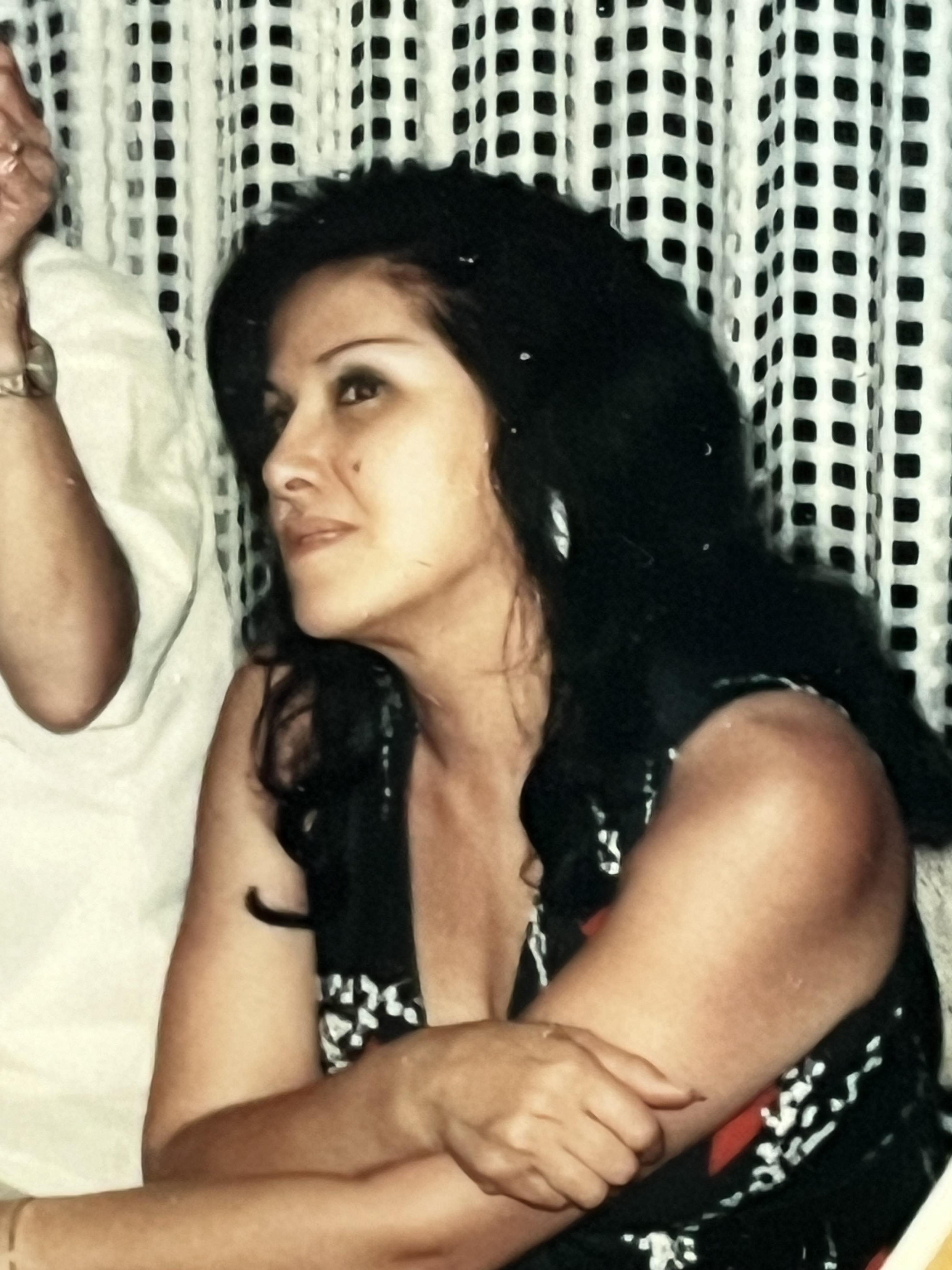 A woman is sitting and looking to the side while another person is nearby.