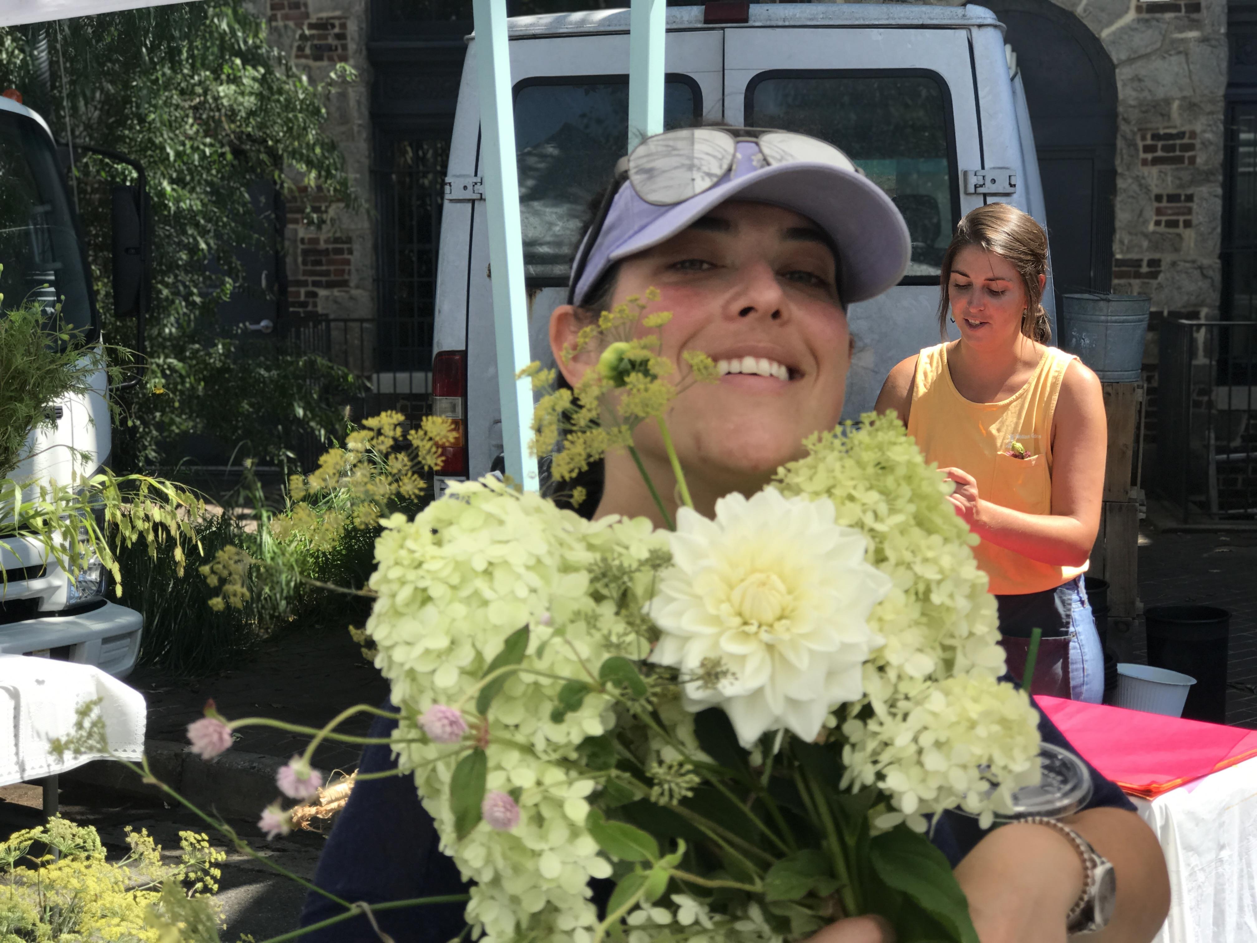A woman holding flowers in front of a van