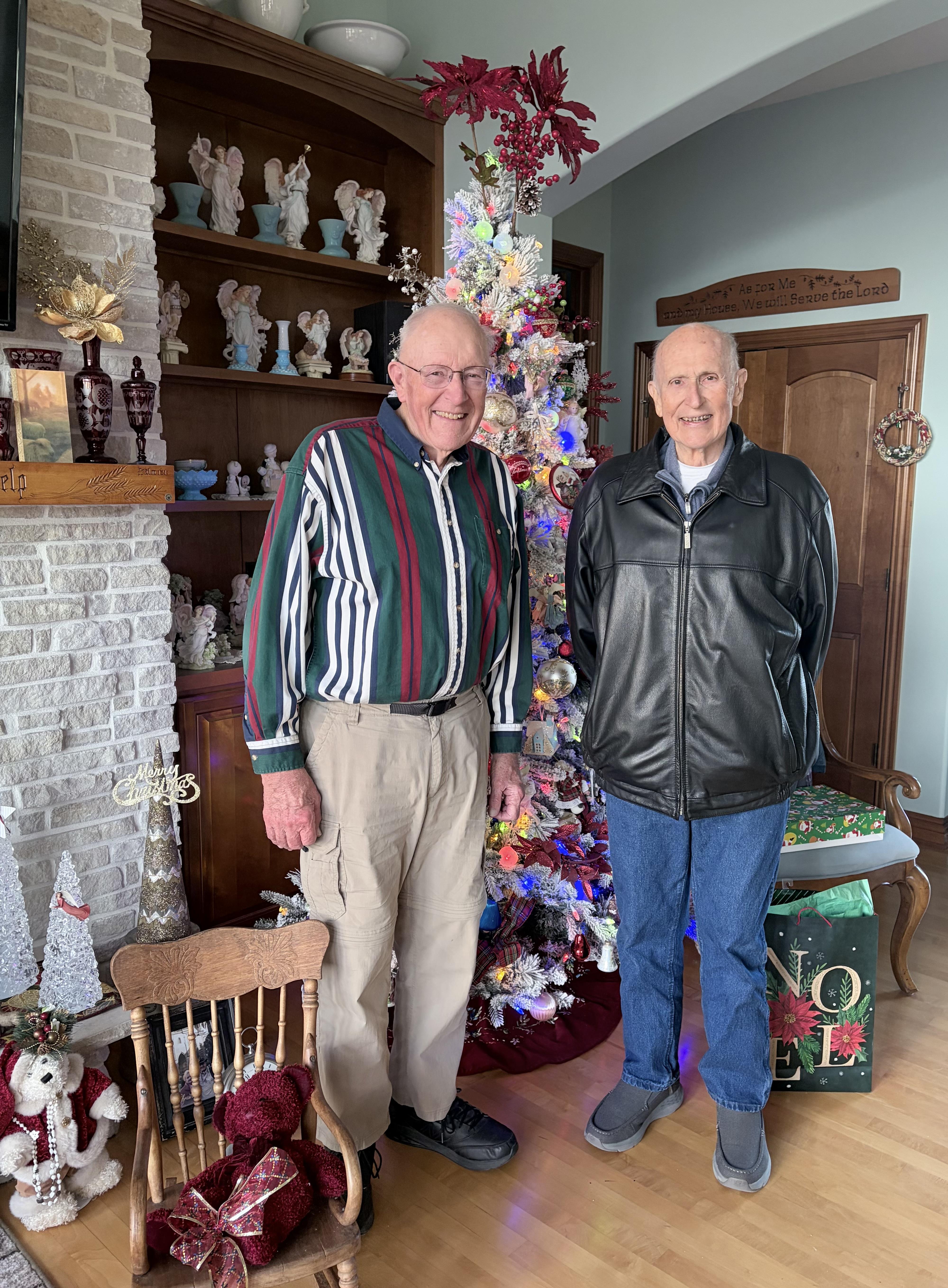 Two men standing in front of a christmas tree